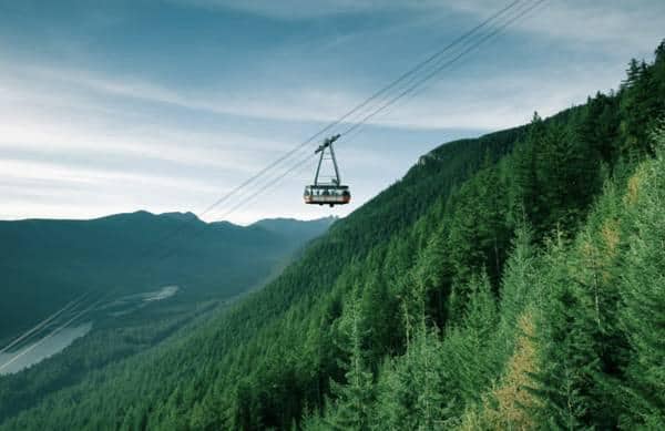 Cable car ascending over lush green mountain forest in BC, Canada, ideal for Vancouver real estate and outdoor adventure enthusiasts.
