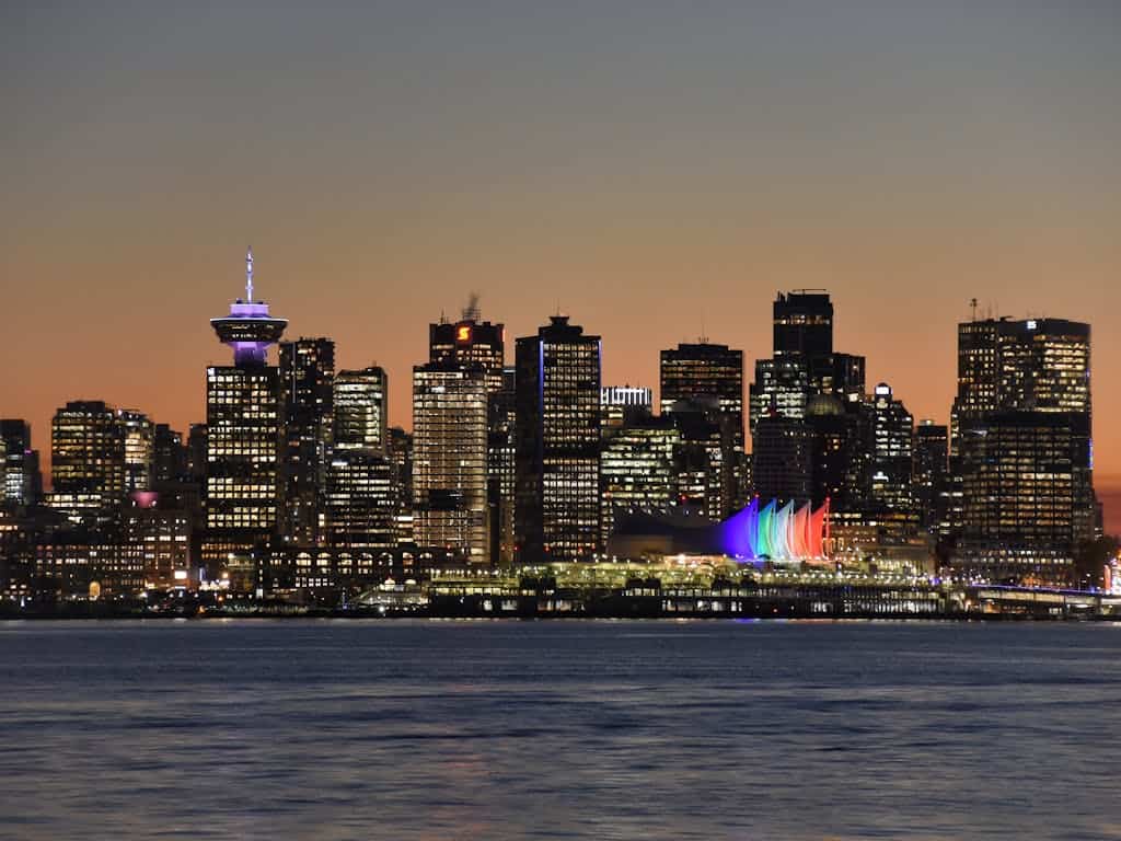 Vancouver skyline at twilight with illuminated buildings and Harbour Centre CN Tower, showcasing urban real estate and waterfront views in British Columbia.