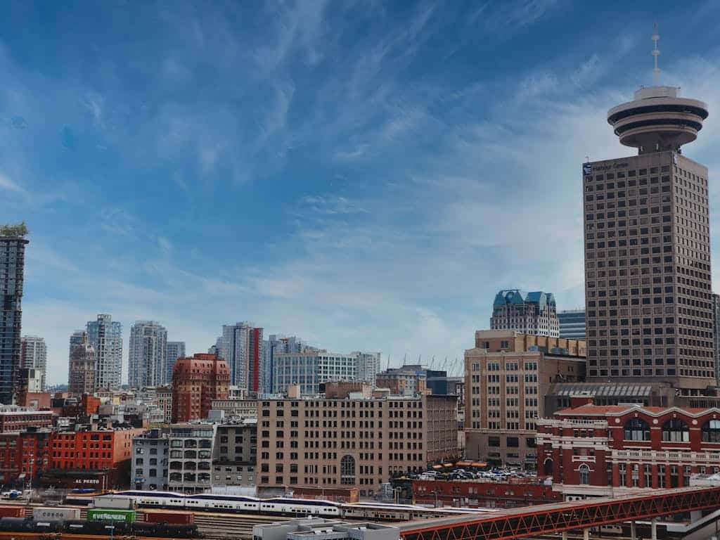 Vancouver city skyline with skyscrapers and the Harbour Centre observation tower in the background, showcasing urban real estate and vibrant city life.