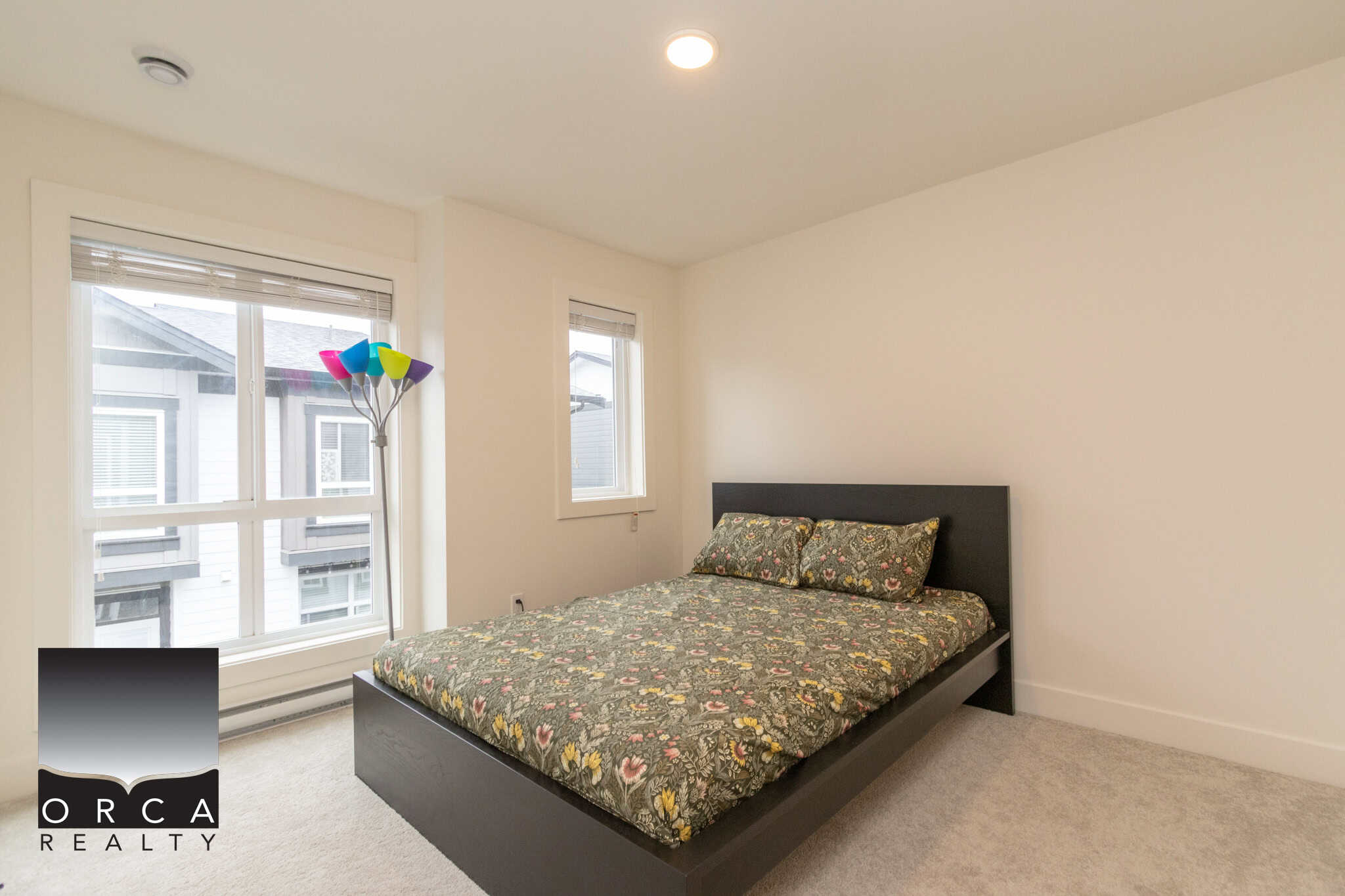 Bright modern bedroom with large windows and neutral decor, ideal for home buyers and real estate listings in Vancouver, BC.