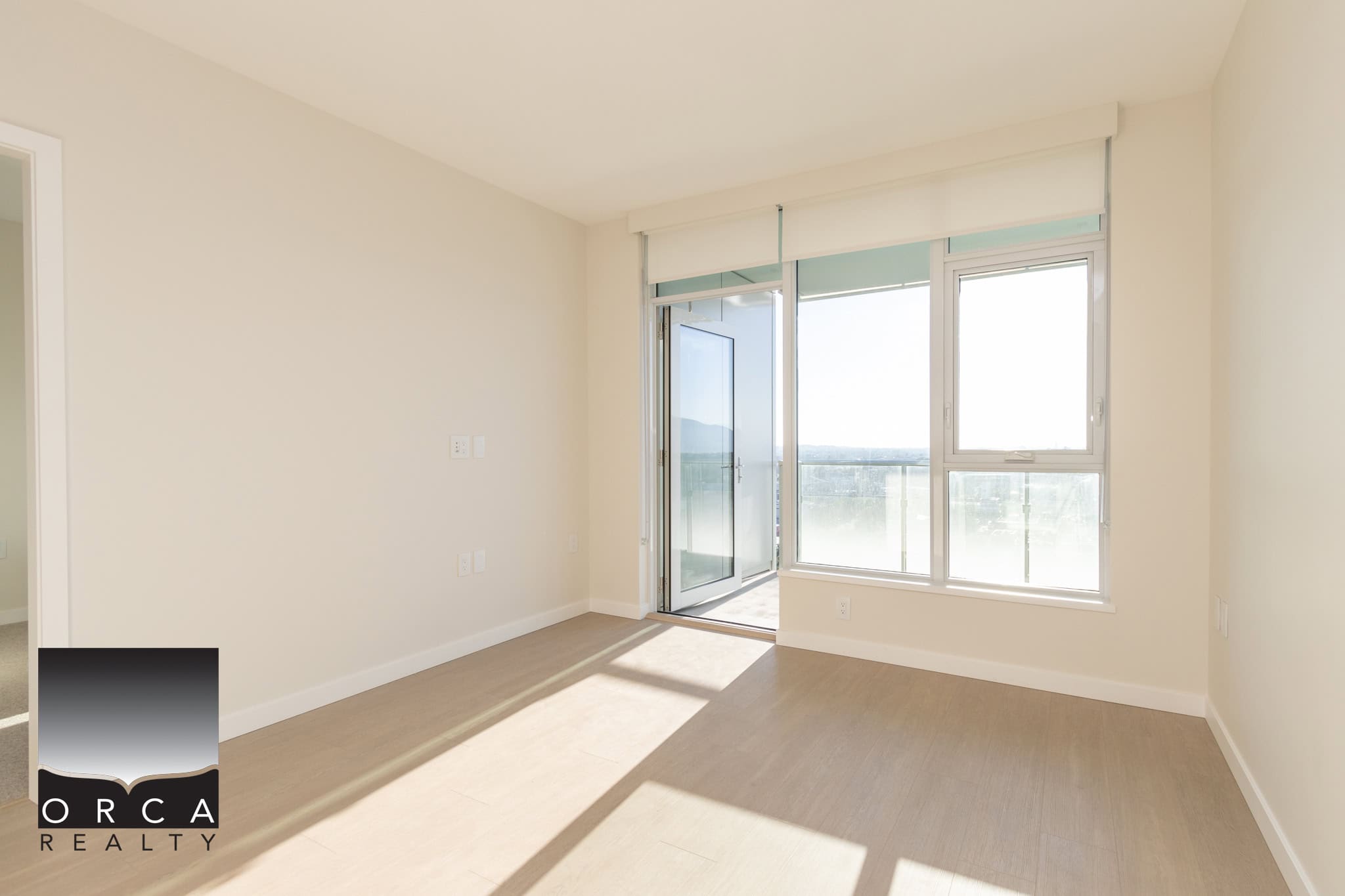 Bright modern living room with large windows and balcony access, showcasing Vancouver skyline views, ideal for Toronto real estate buyers seeking spacious, contemporary condos.