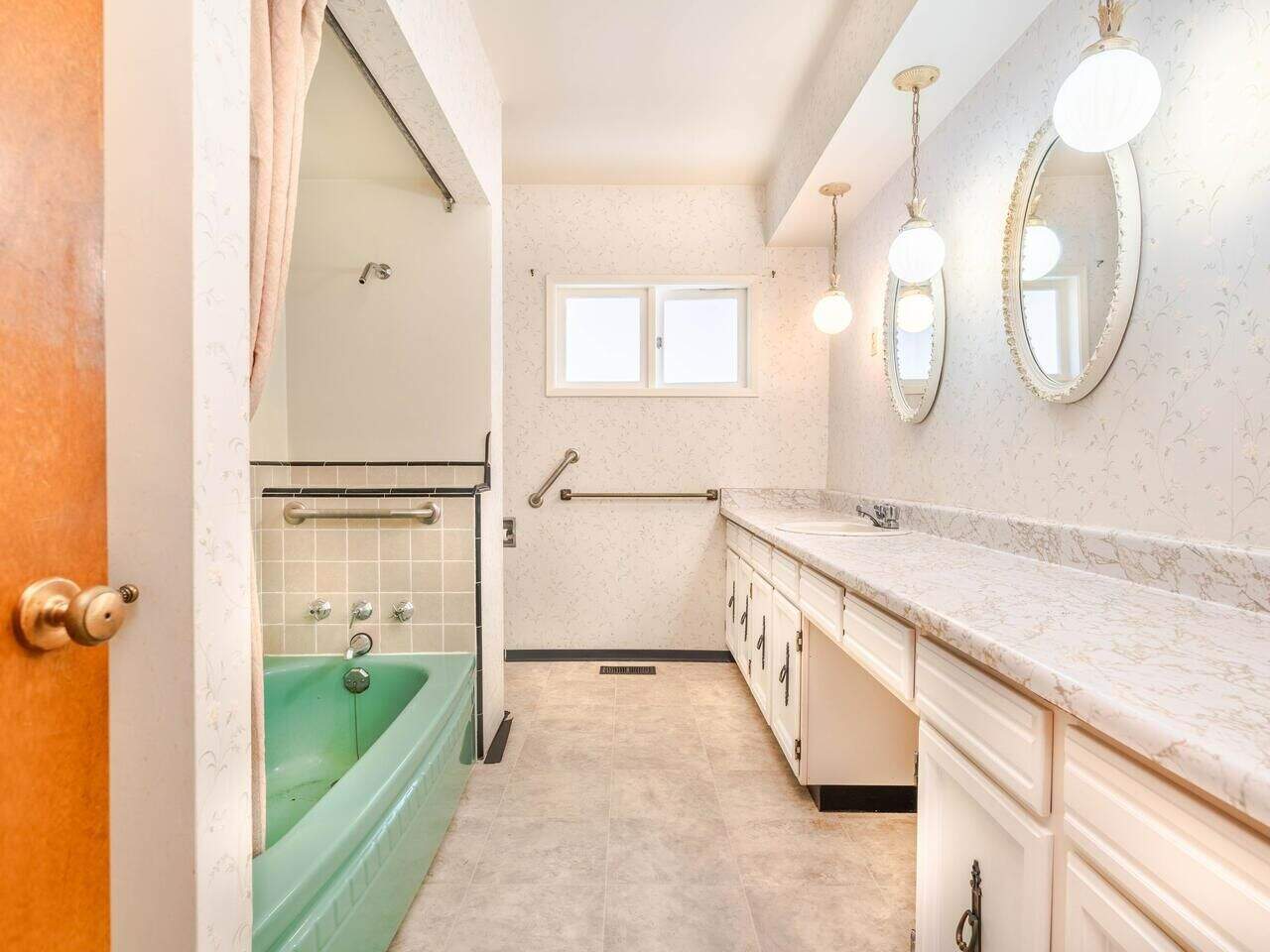 Vintage bathroom with a green bathtub, white cabinetry, patterned countertops, and wall mirrors, featuring natural light and functional fixtures, ideal for home renovation ideas.