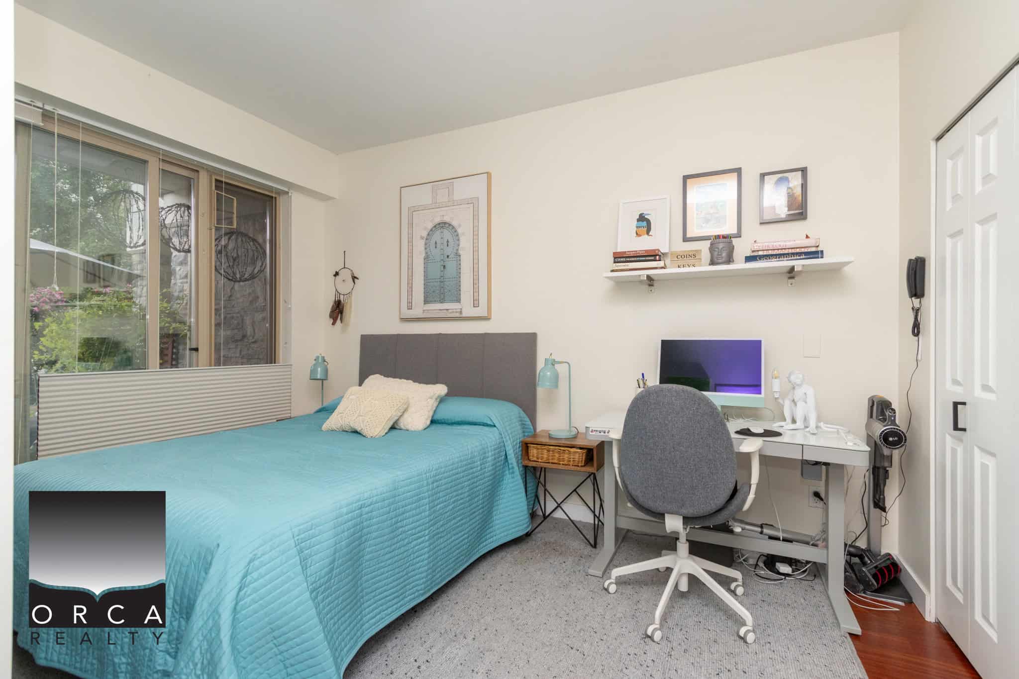 Bright cozy bedroom with a single bed, home office setup, and stylish decor in a Vancouver area apartment, showcasing comfort and functional living space by Orca Realty Inc.