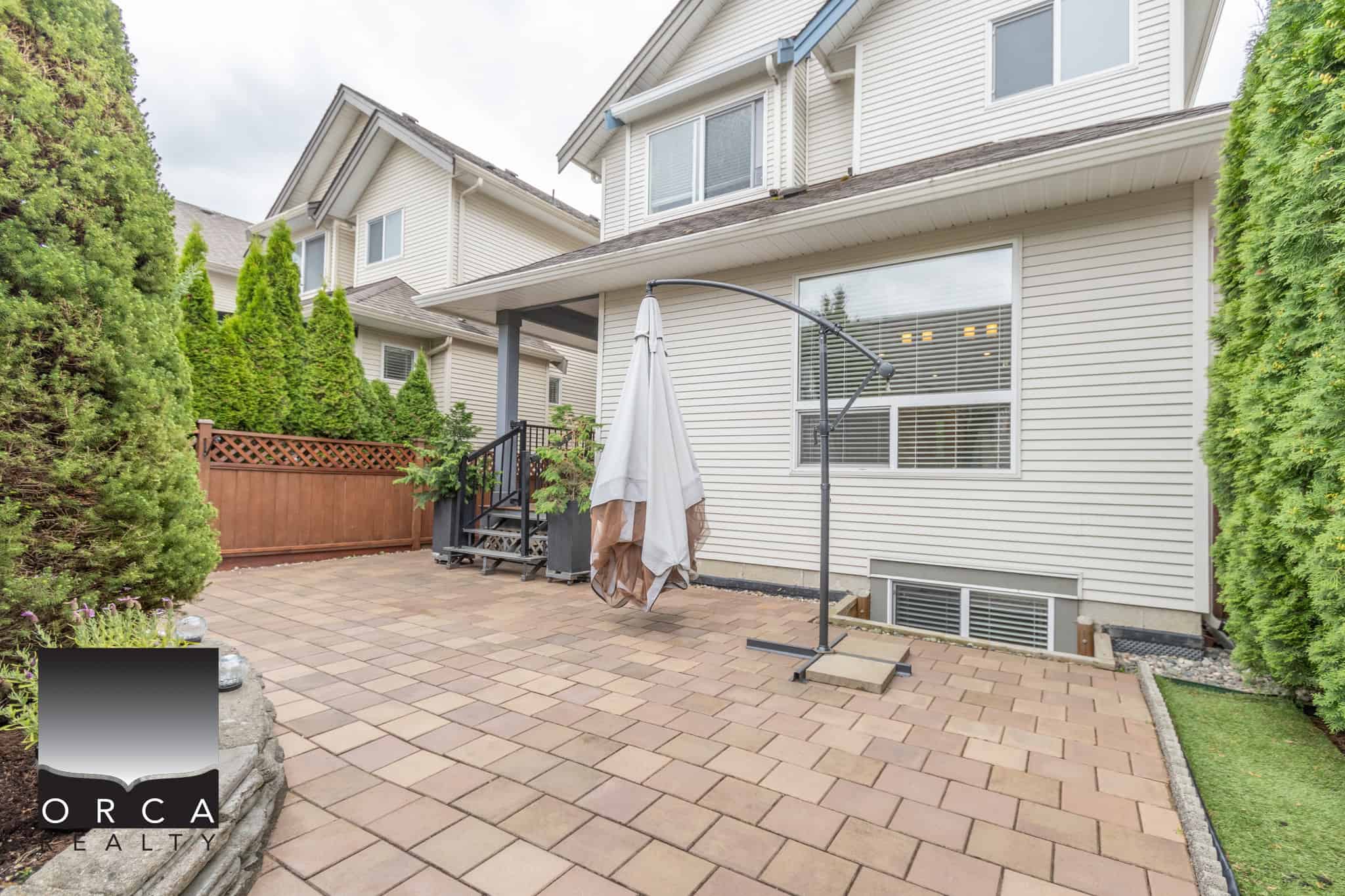 Spacious private backyard patio with pavers, surrounded by lush greenery, perfect for outdoor entertaining and relaxation in a family-friendly residential neighbourhood.