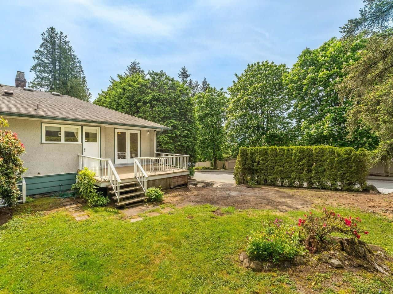 Spacious backyard with lush greenery and a small wooden deck, ideal for outdoor living and entertaining in a Vancouver area home listed by Orca Realty Inc.