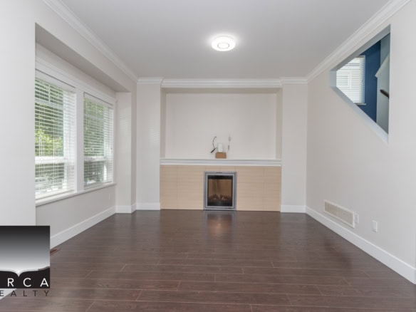 Spacious living room with hardwood flooring, large windows, and a fireplace in a modern house listing by Orca Realty Inc.
