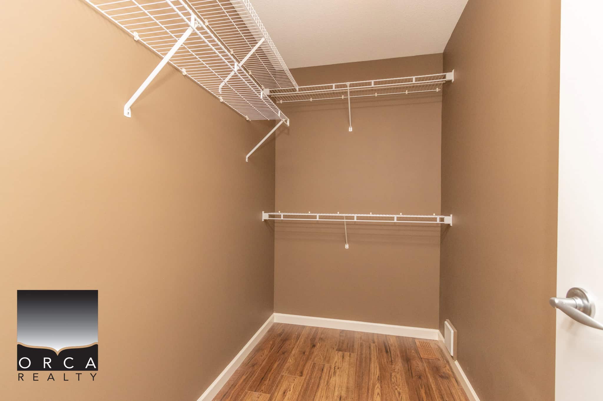 Spacious walk-in closet with wire shelving and hardwood flooring, ideal for organizing clothes and accessories, showcasing a well-maintained property by Orca Realty Inc.