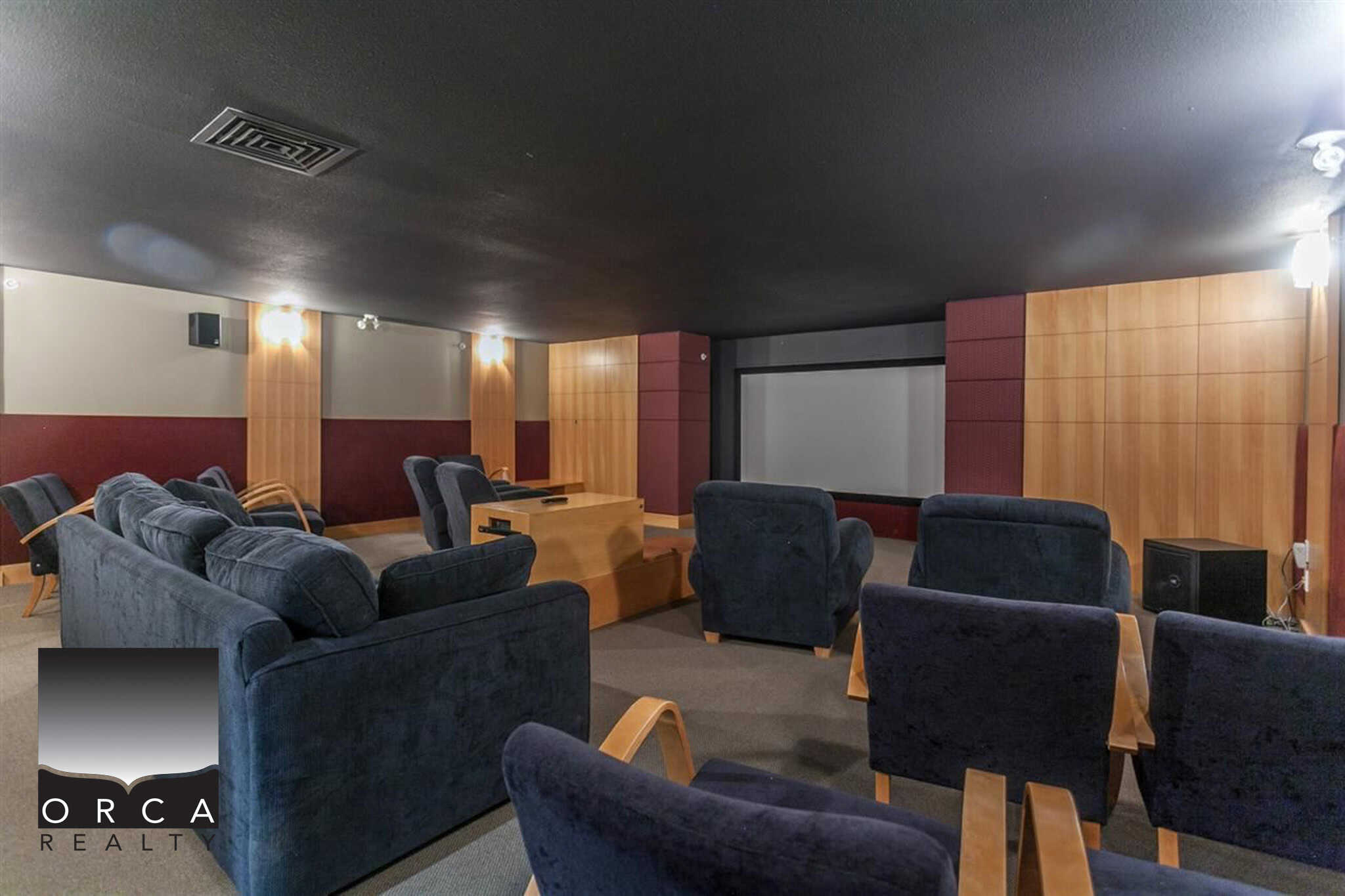 Comfortable home theatre room with plush seating, large screen, and sound system, ideal for movie nights and entertainment in a modern residence or commercial space.