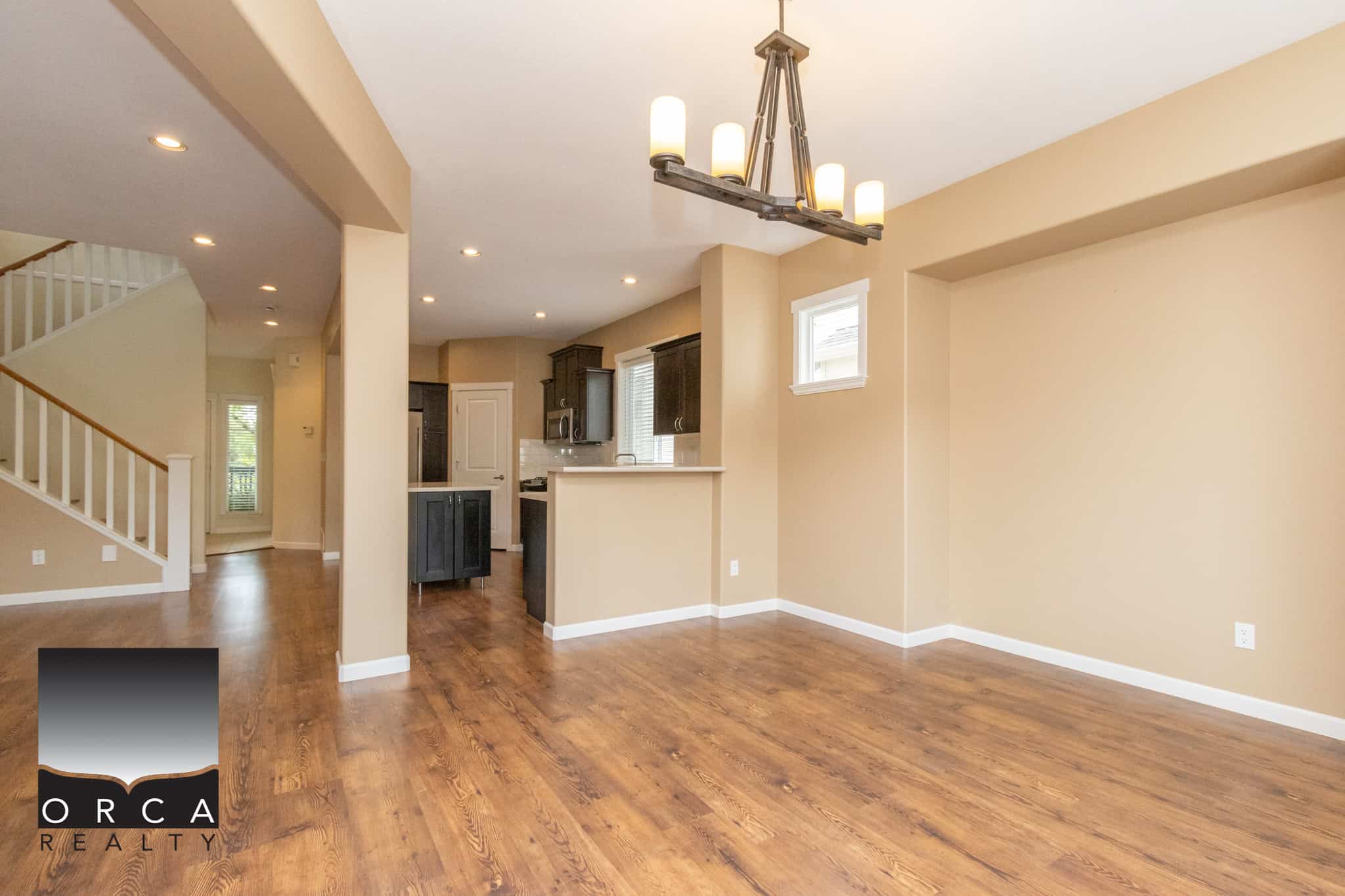 Spacious open-concept living and dining area with hardwood floors, modern lighting, and neutral walls in a Vancouver-style home, ideal for families and entertaining.