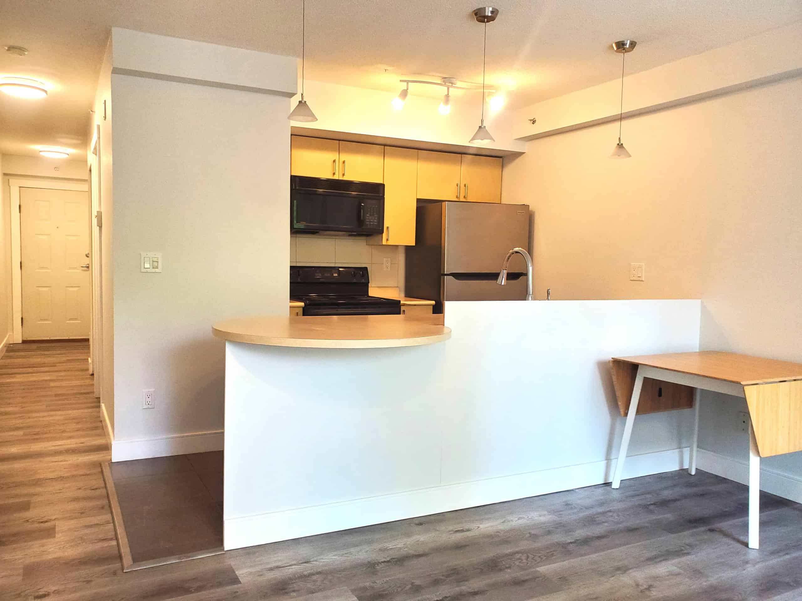 Bright modern kitchen with open layout, featuring stainless steel appliances, light wood cabinets, and a cozy breakfast bar, ideal for contemporary urban living in Vancouver.