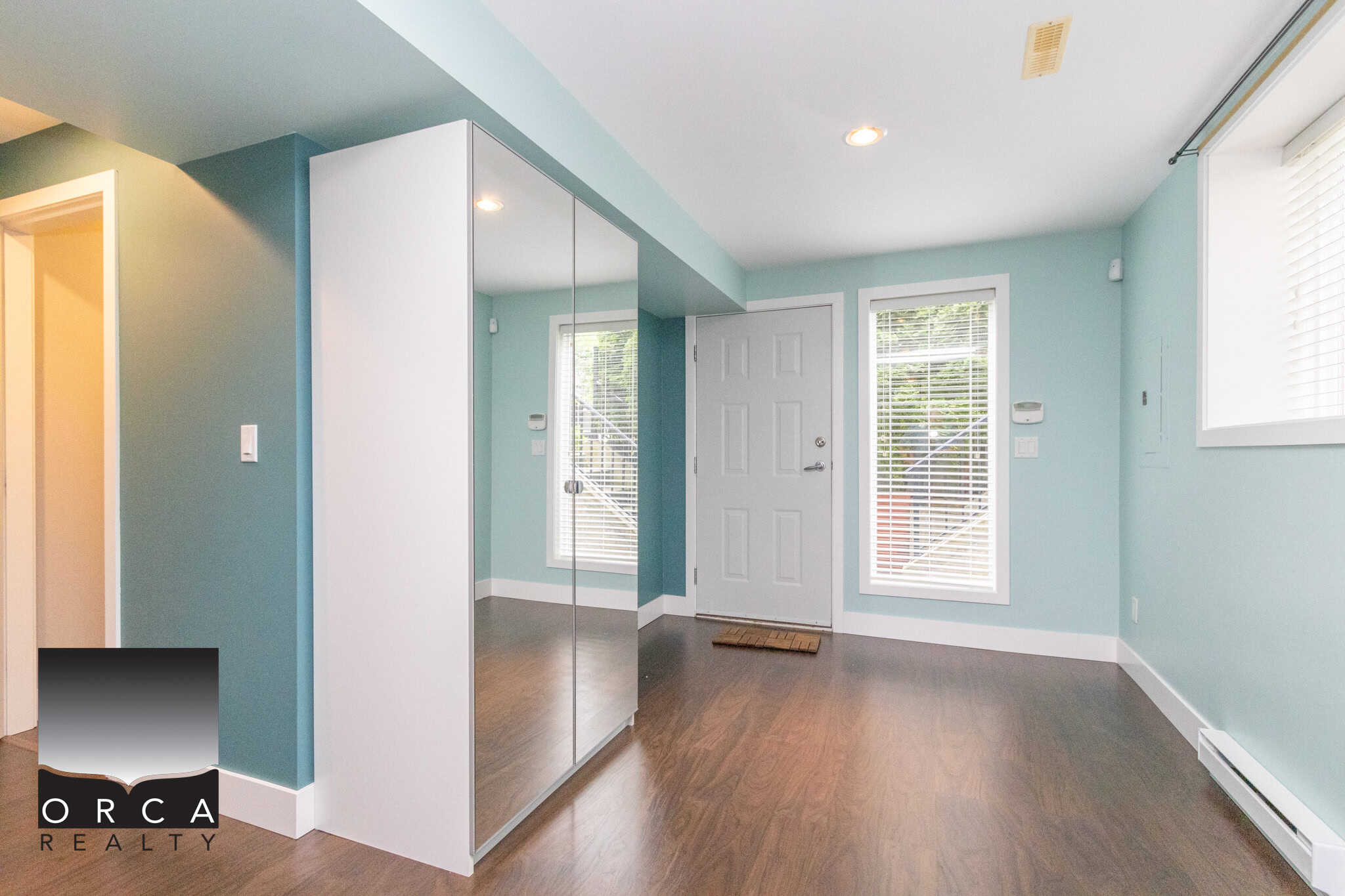 Bright and welcoming home interior with light blue walls, hardwood floors, and large windows, showcasing a modern living space perfect for Canadian families seeking real estate in BC.