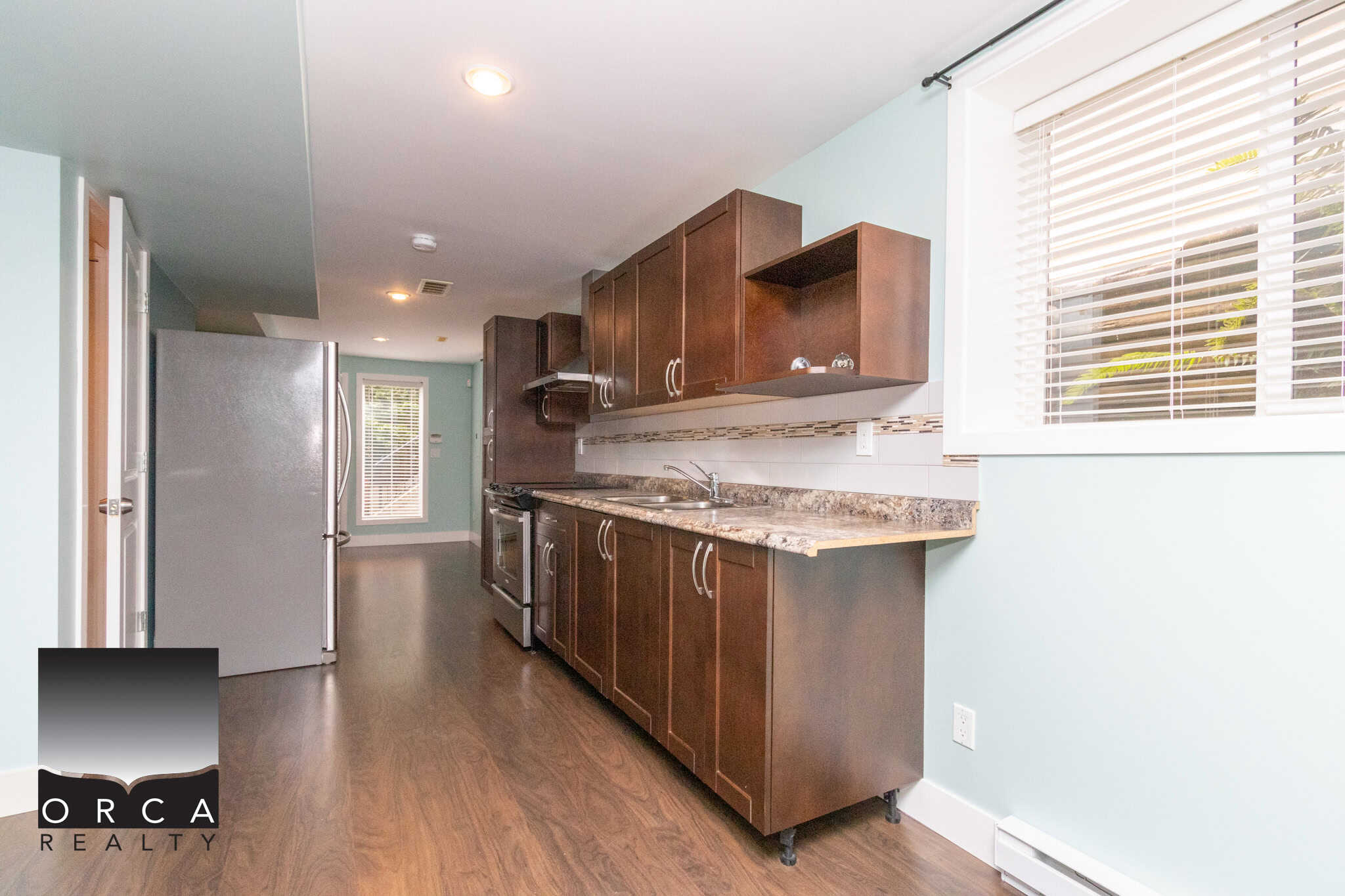Modern kitchen with dark wood cabinetry, granite countertops, stainless steel appliances, and ample natural light, showcasing a stylish and functional space for home living and real estate listings.