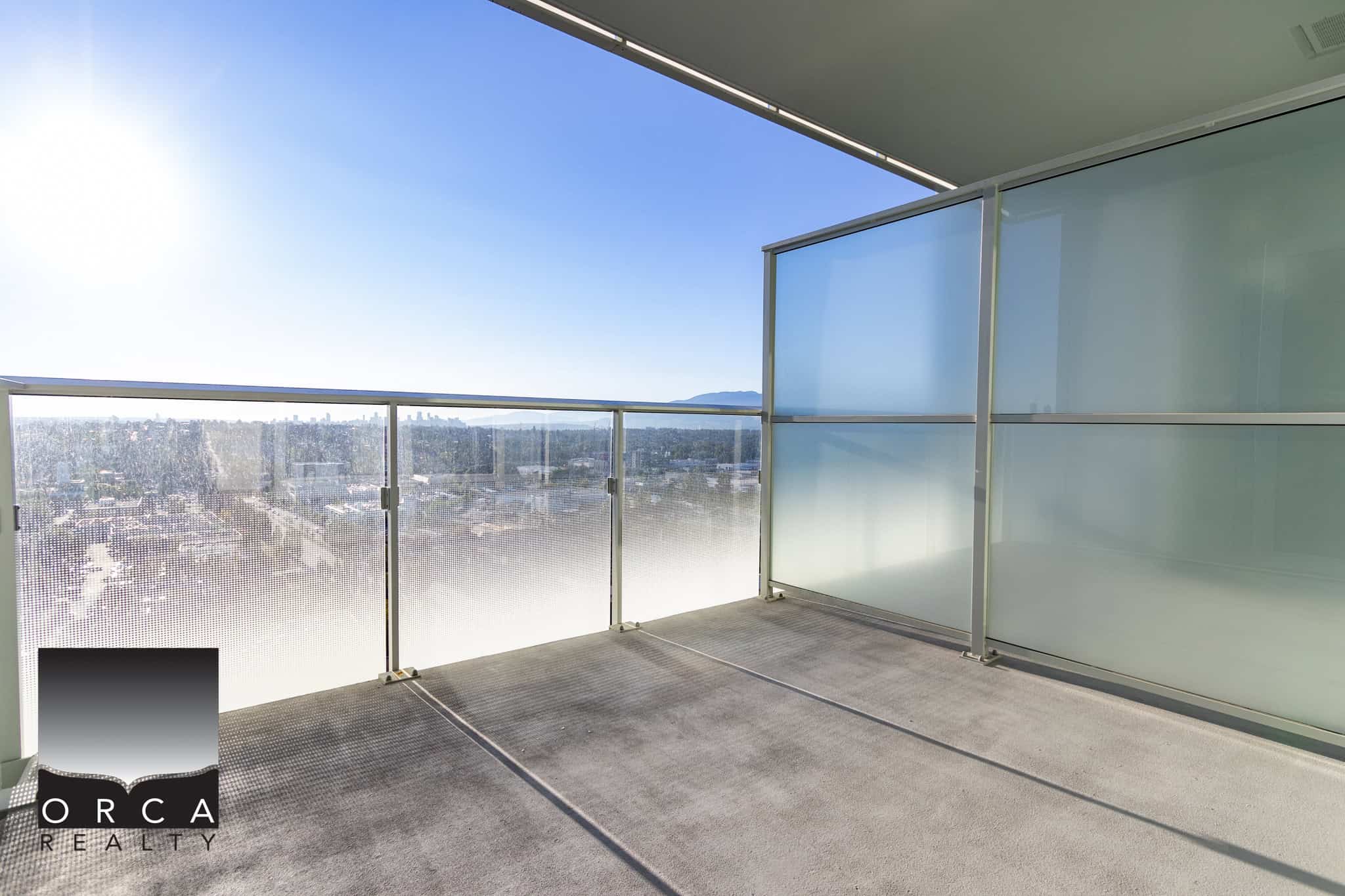 Modern high-rise balcony with glass railing offering stunning city and mountain views in Vancouver, BC, ideal for enjoying outdoor living in the heart of the city.