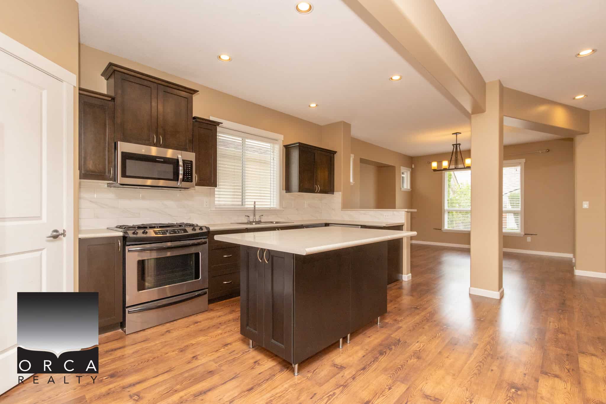 Modern kitchen with dark wood cabinets, stainless steel appliances, and a spacious island, perfect for family living and entertaining in a family-friendly neighbourhood.