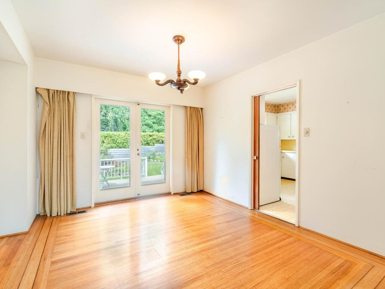 Bright living room with sliding glass doors opening to backyard, hardwood floors, and natural light, ideal for Vancouver Island real estate buyers.