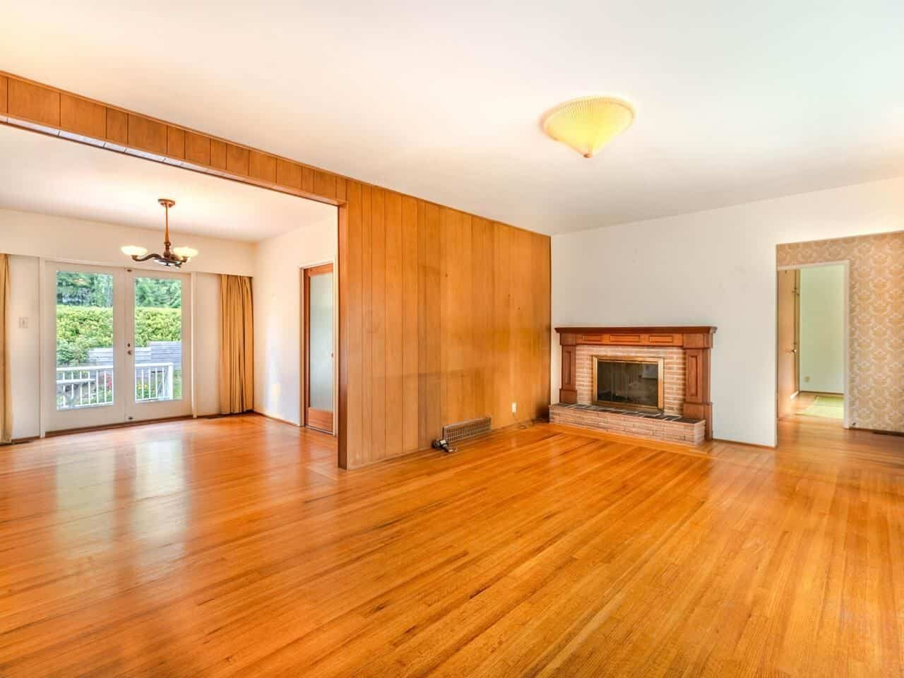 Bright living room with hardwood floors, brick fireplace, and natural light from large windows and glass doors leading to outdoor space, ideal for Vancouver Island homes.
