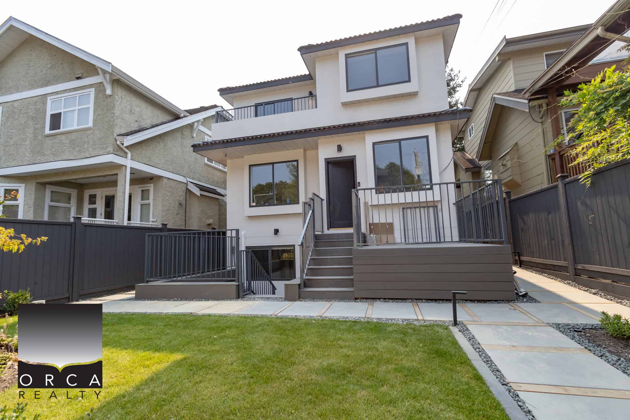 Modern detached townhouse with contemporary design, spacious patio, and well-maintained lawn in a vibrant neighbourhood, perfect for families and real estate investment in Vancouver.