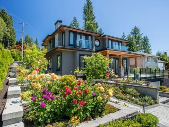 Modern luxury house with landscaped garden, vibrant flowers, and contemporary design, offered by Orca Realty Inc. in BC.