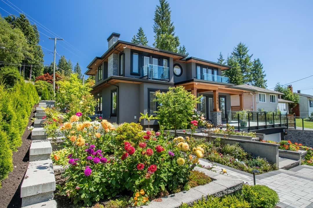 Modern luxury house with landscaped garden, vibrant flowers, and contemporary design, offered by Orca Realty Inc. in BC.