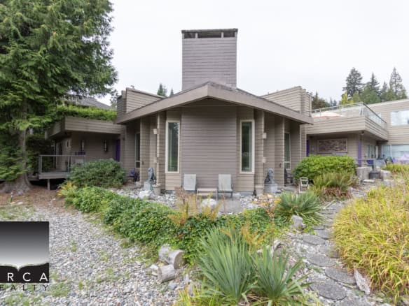 Modern lakeside home with lush landscaping, extensive decks, and scenic views, perfect for Vancouver Island real estate buyers seeking luxury properties.