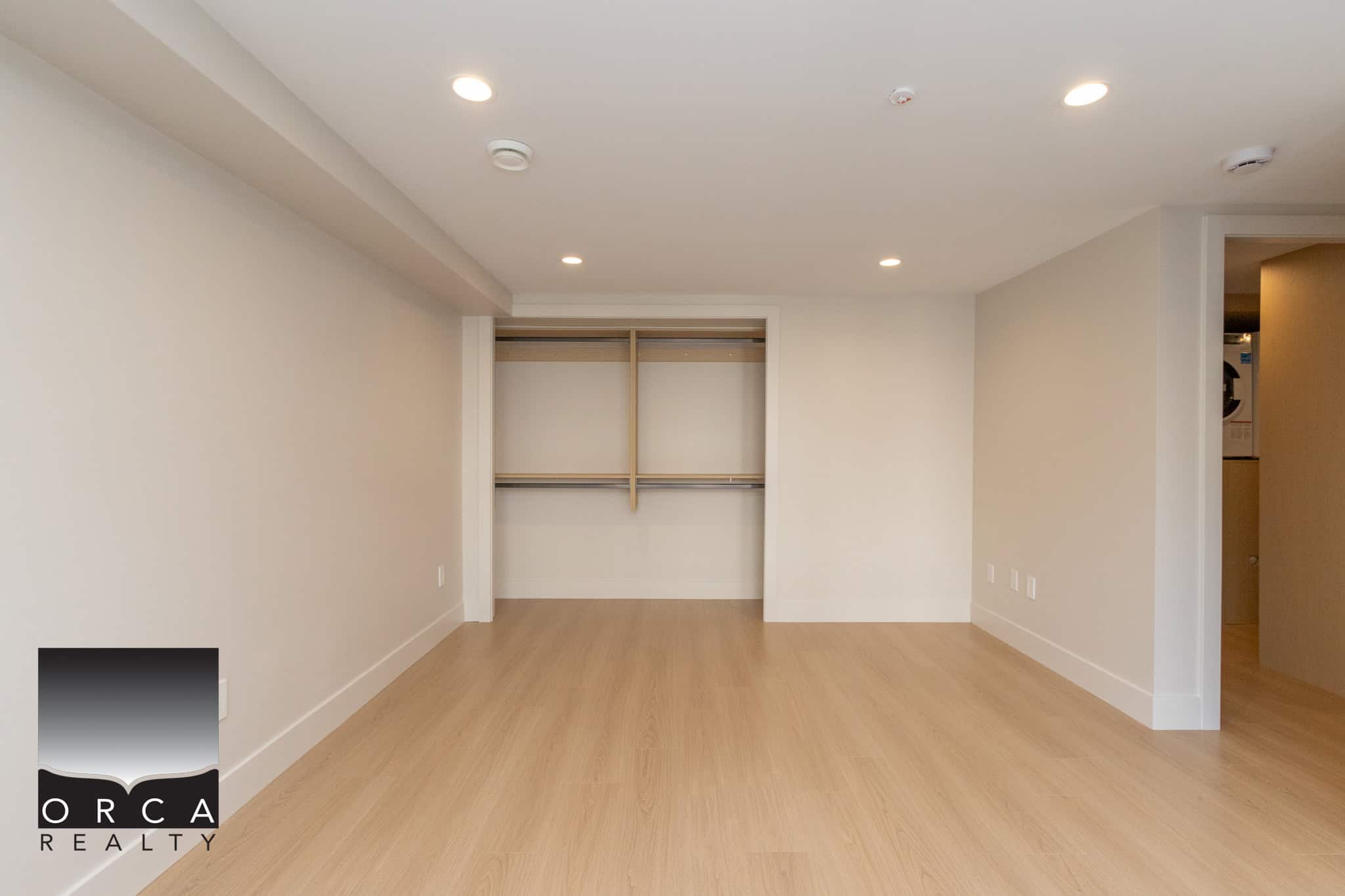 Spacious empty bedroom with built-in closet and light wood flooring, perfect for Vancouver homebuyers seeking modern real estate options.