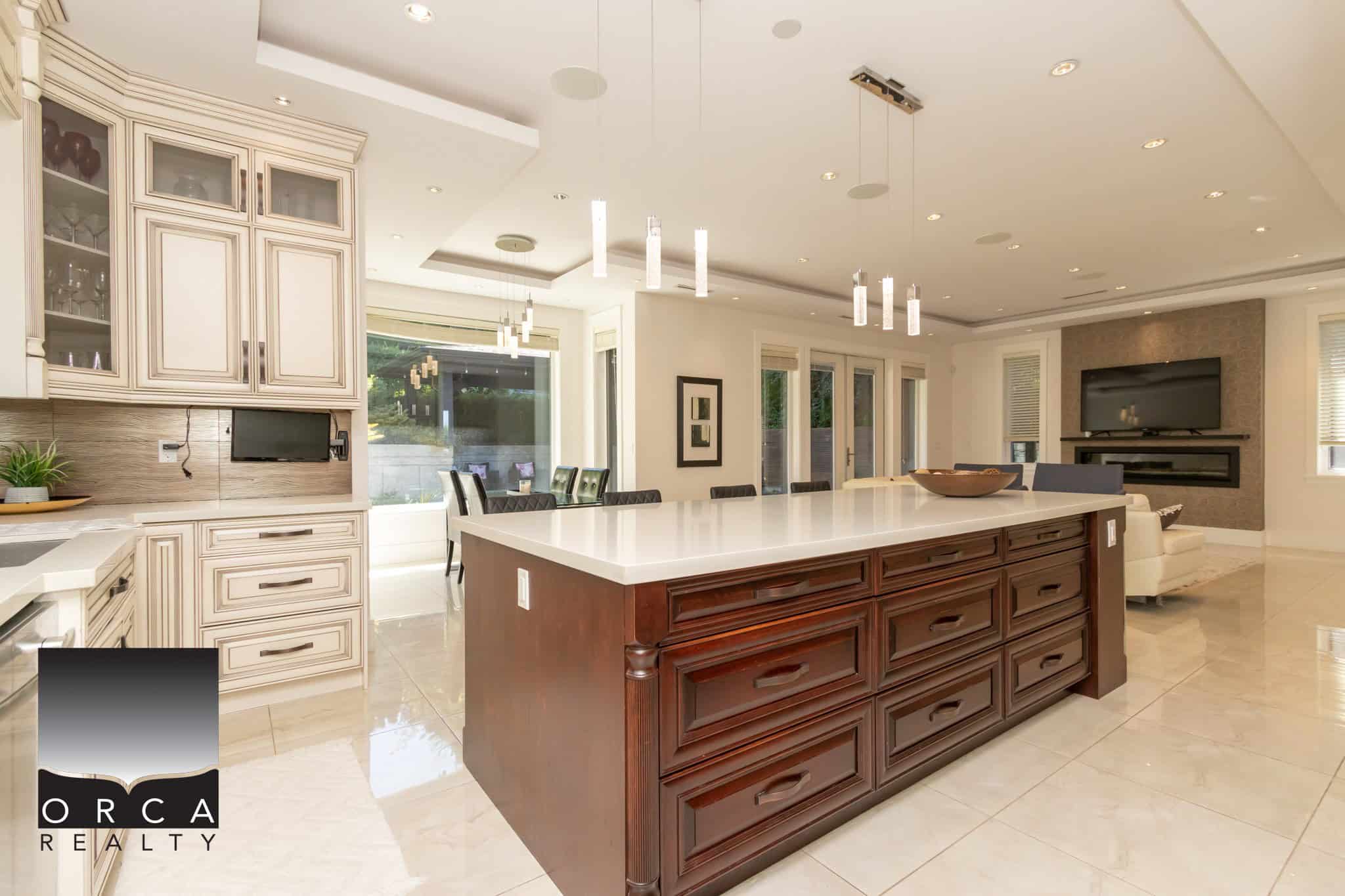 Spacious modern kitchen with large island, elegant cabinetry, and contemporary lighting, perfect for family gatherings and entertaining in a luxurious home.