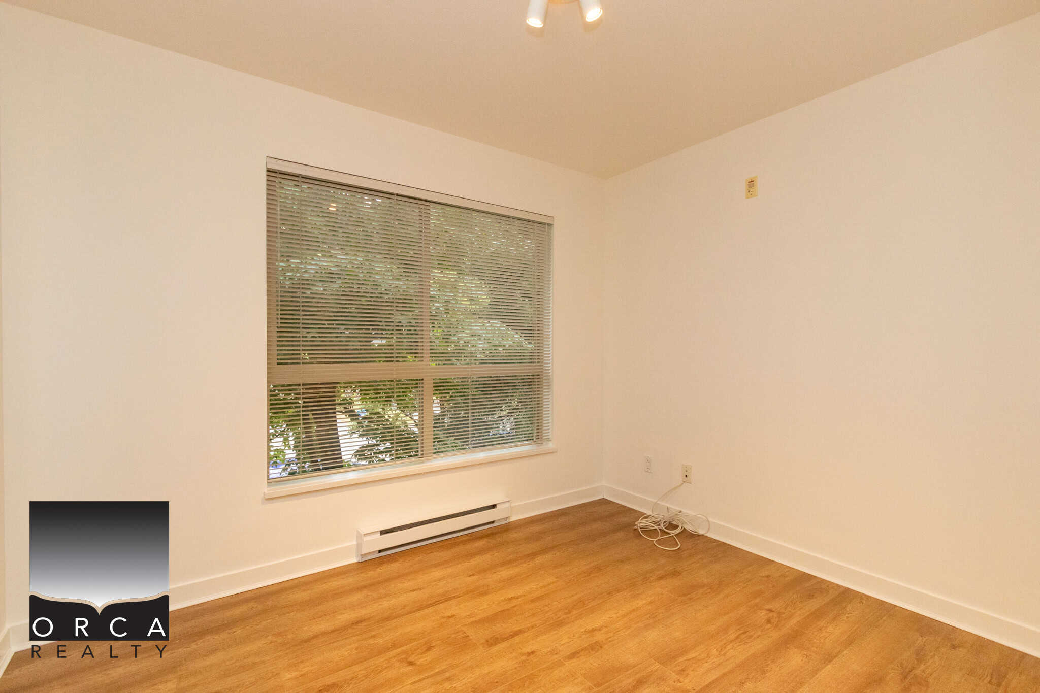 Bright vacant room with large window and hardwood flooring in a modern Vancouver home, ideal for real estate showing or rental listing in BC.