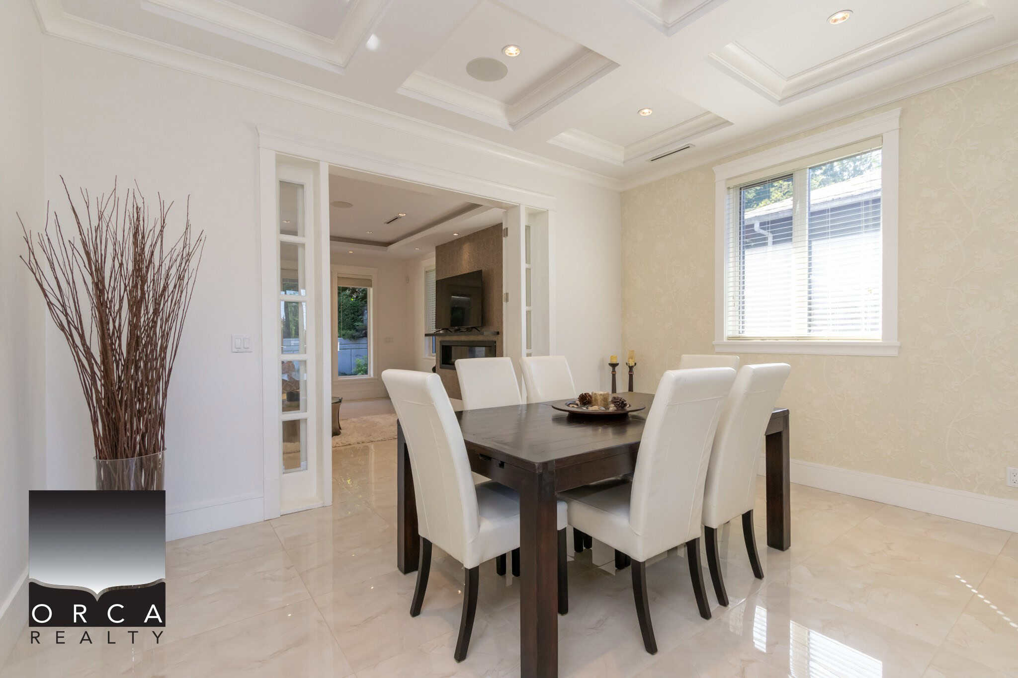 Spacious dining room with elegant white walls, large windows providing natural light, and a modern decor aesthetic. Perfect for family gatherings and entertaining guests.