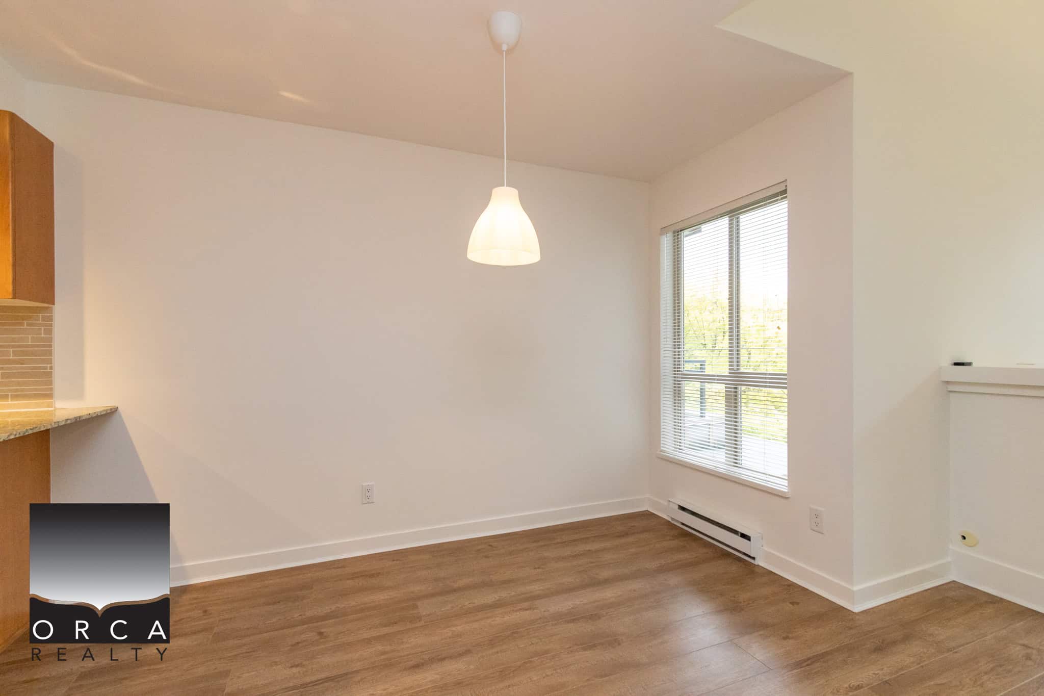 Bright and spacious living area in a modern apartment, featuring large windows, hardwood flooring, and neutral wall colors, ideal for comfortable urban living.