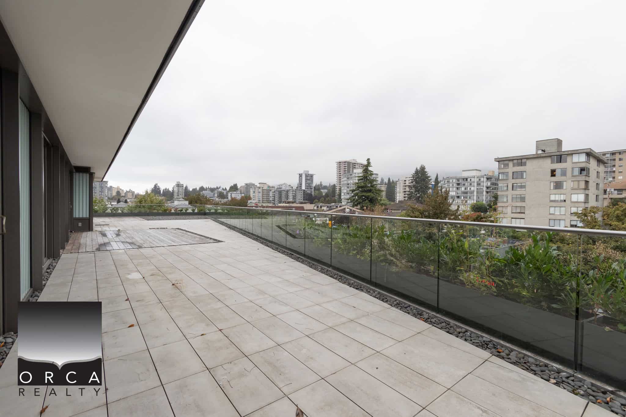 Spacious modern balcony terrace with glass railing and city skyline view, ideal for real estate listings, outdoor living, and property showcasing in Vancouver.