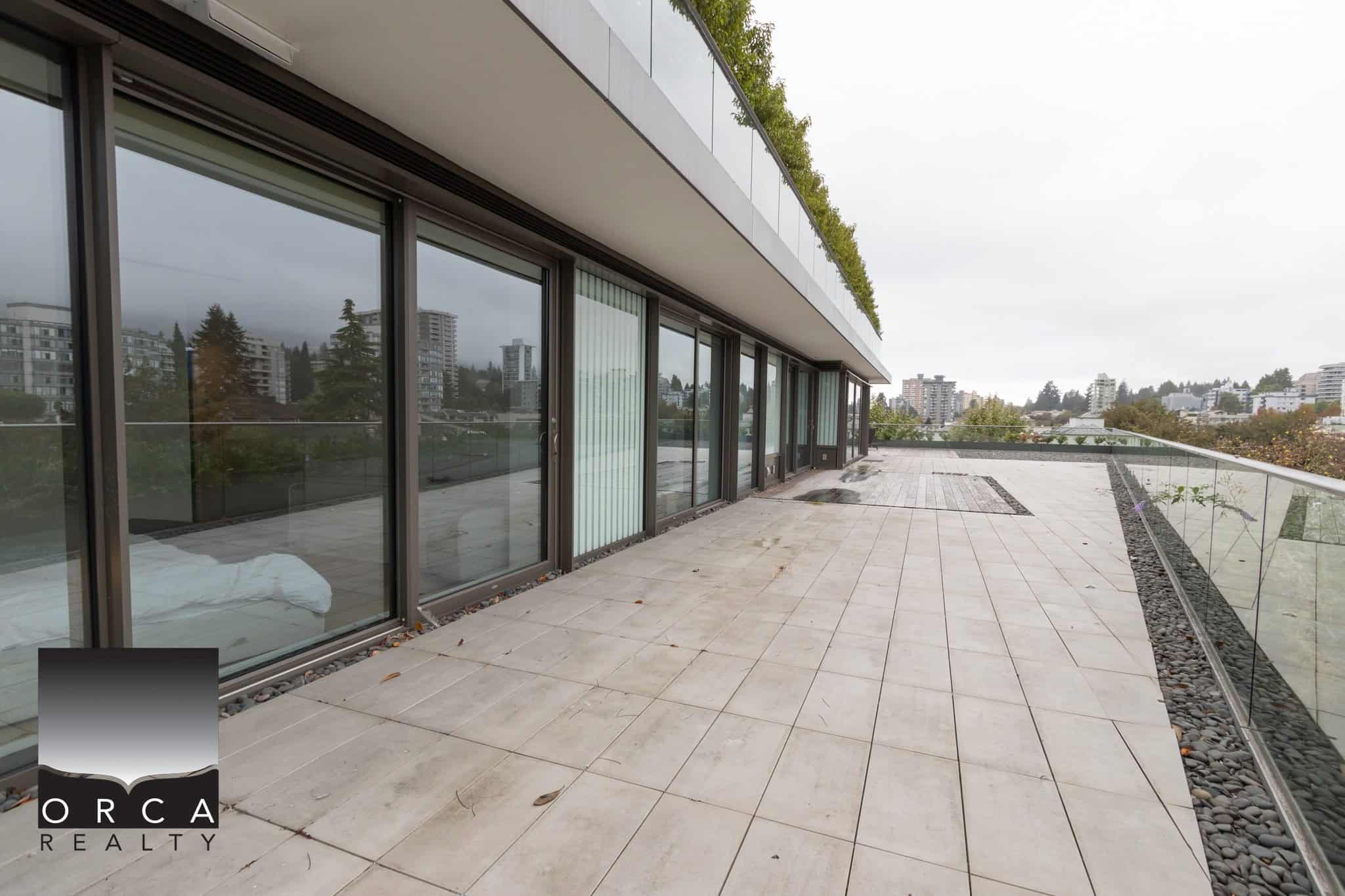 Spacious modern balcony with glass railing and city view, located at Orca Realty Inc. offering premium Vancouver real estate options and stunning property listings in British Columbia.
