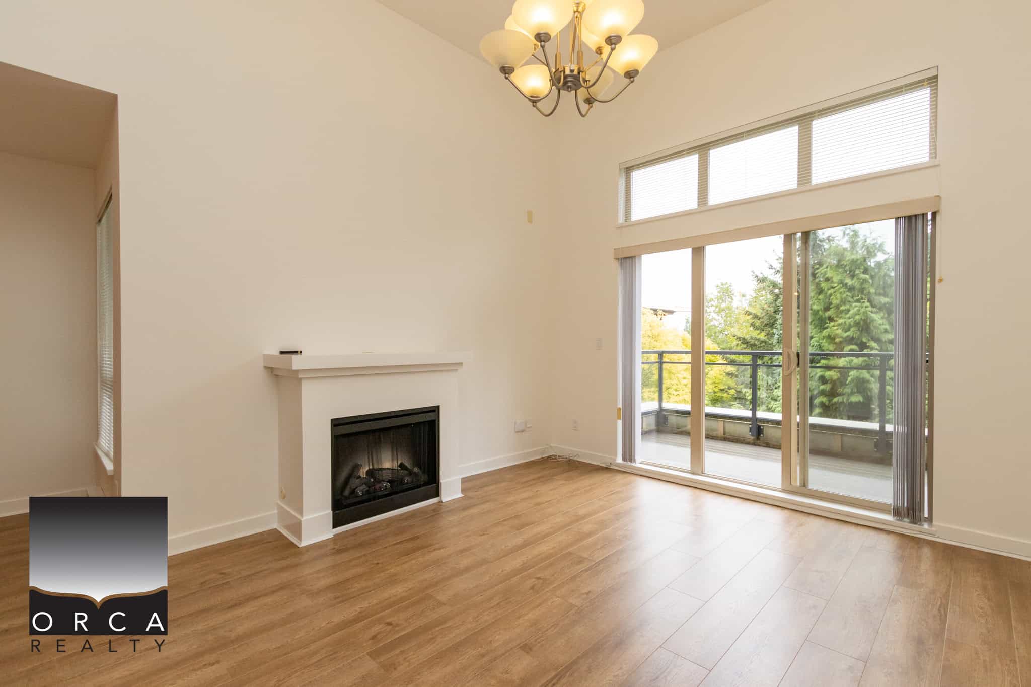 Bright living room with large glass doors leading to balcony, modern fireplace, high ceilings, and abundant natural light, perfect for Vancouver real estate buyer interests.