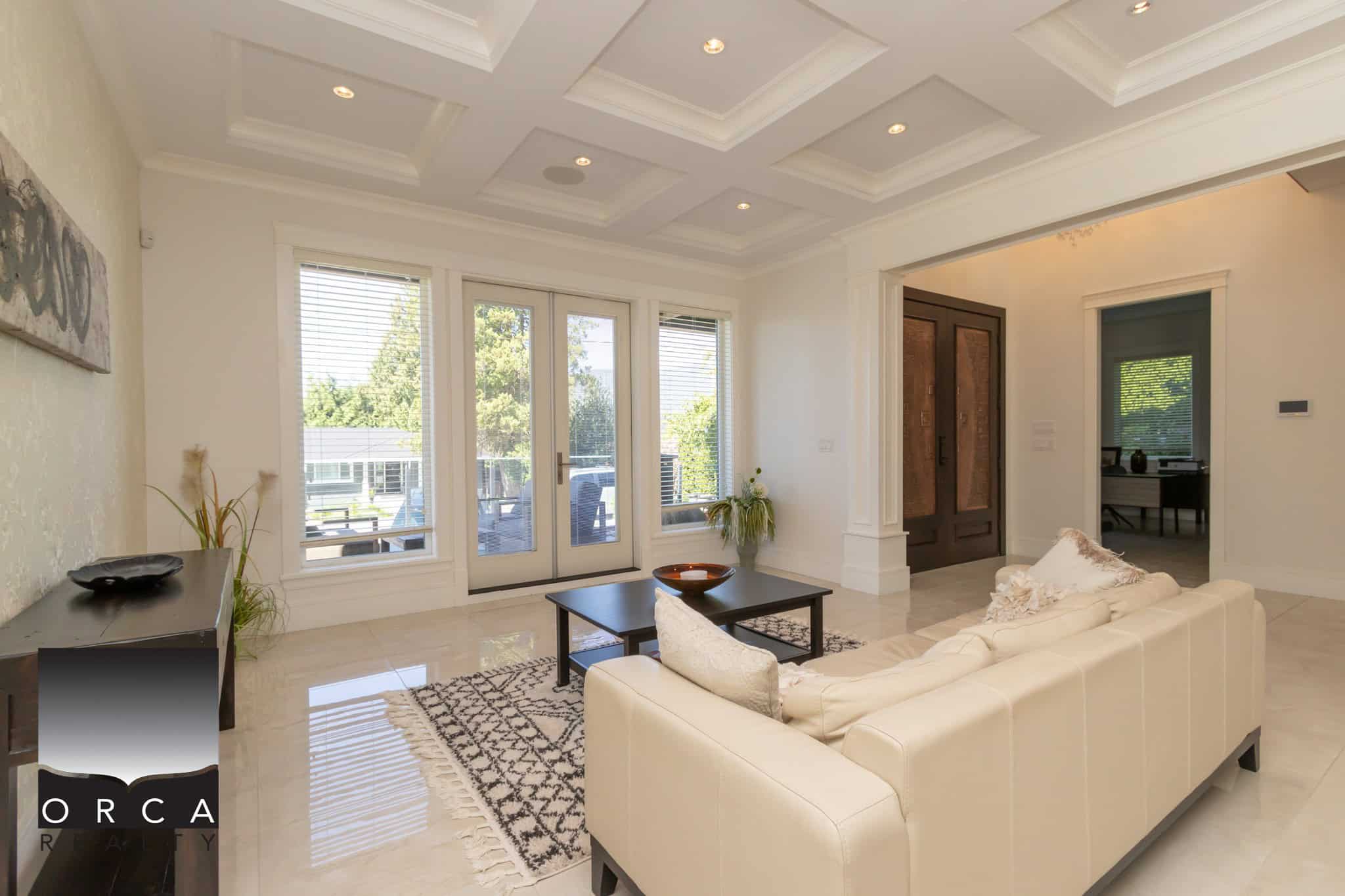 Bright modern living room with large windows and glass doors, featuring a cozy white sofa, stylish decor, and access to outdoor space, ideal for Vancouver Island real estate listings.