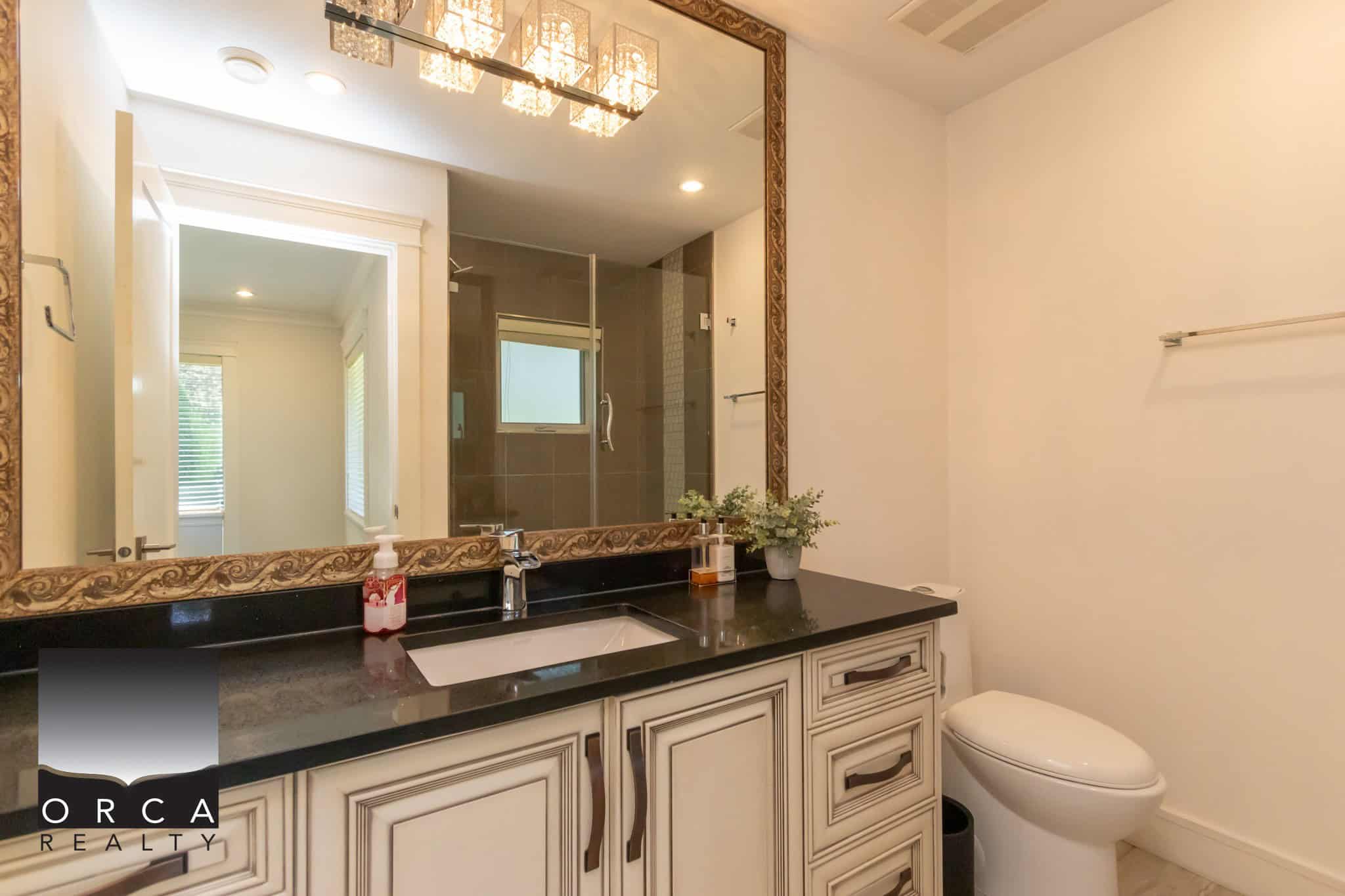 Luxurious bathroom with elegant vanity, framed mirror, modern fixtures, walk-in shower, and stylish decor, perfect for upscale real estate listings in Victoria.