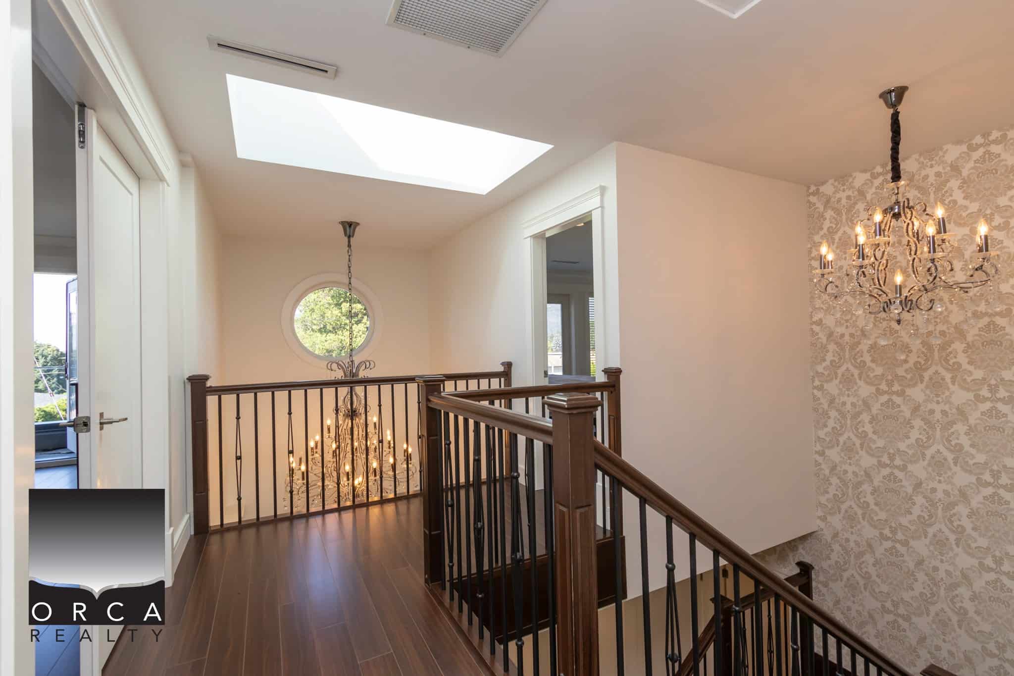 Luxurious upper-floor interior with elegant chandeliers, natural light from skylight, and classic decor, perfect for upscale Vancouver real estate.