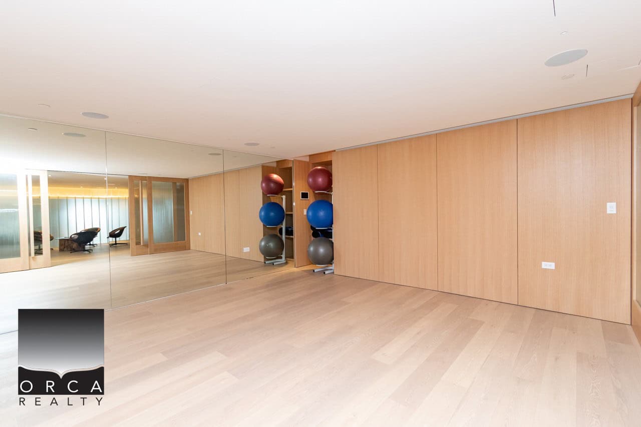 Modern fitness room with wooden flooring, mirrored wall, and exercise balls – ideal for personal training or yoga, part of Orca Realty Inc.'s premier Vancouver Island real estate offerings.