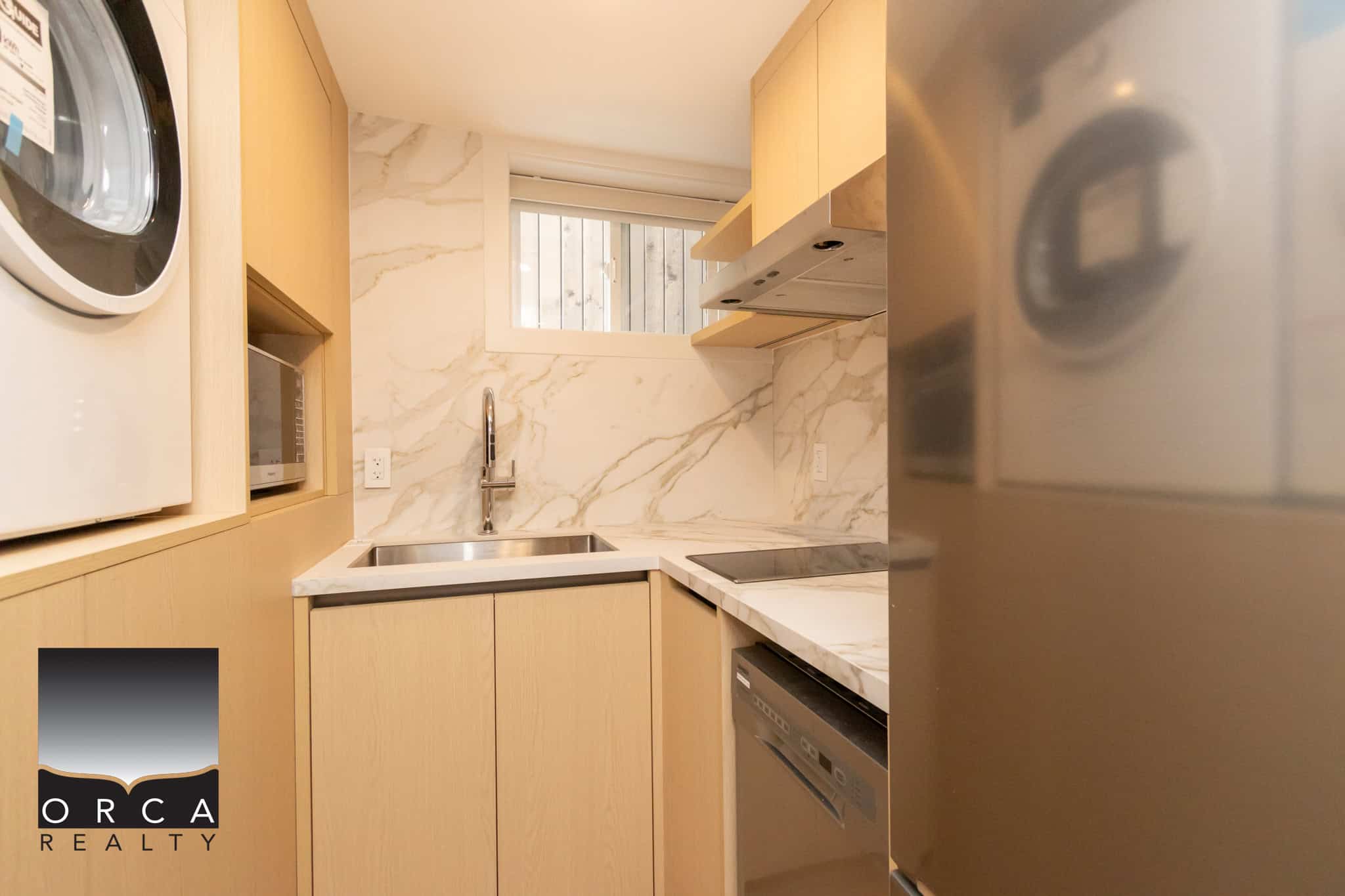 Modern compact kitchen with marble countertops, built-in appliances, and natural wood cabinetry, perfect for city living or investment properties in Vaughan or Toronto.