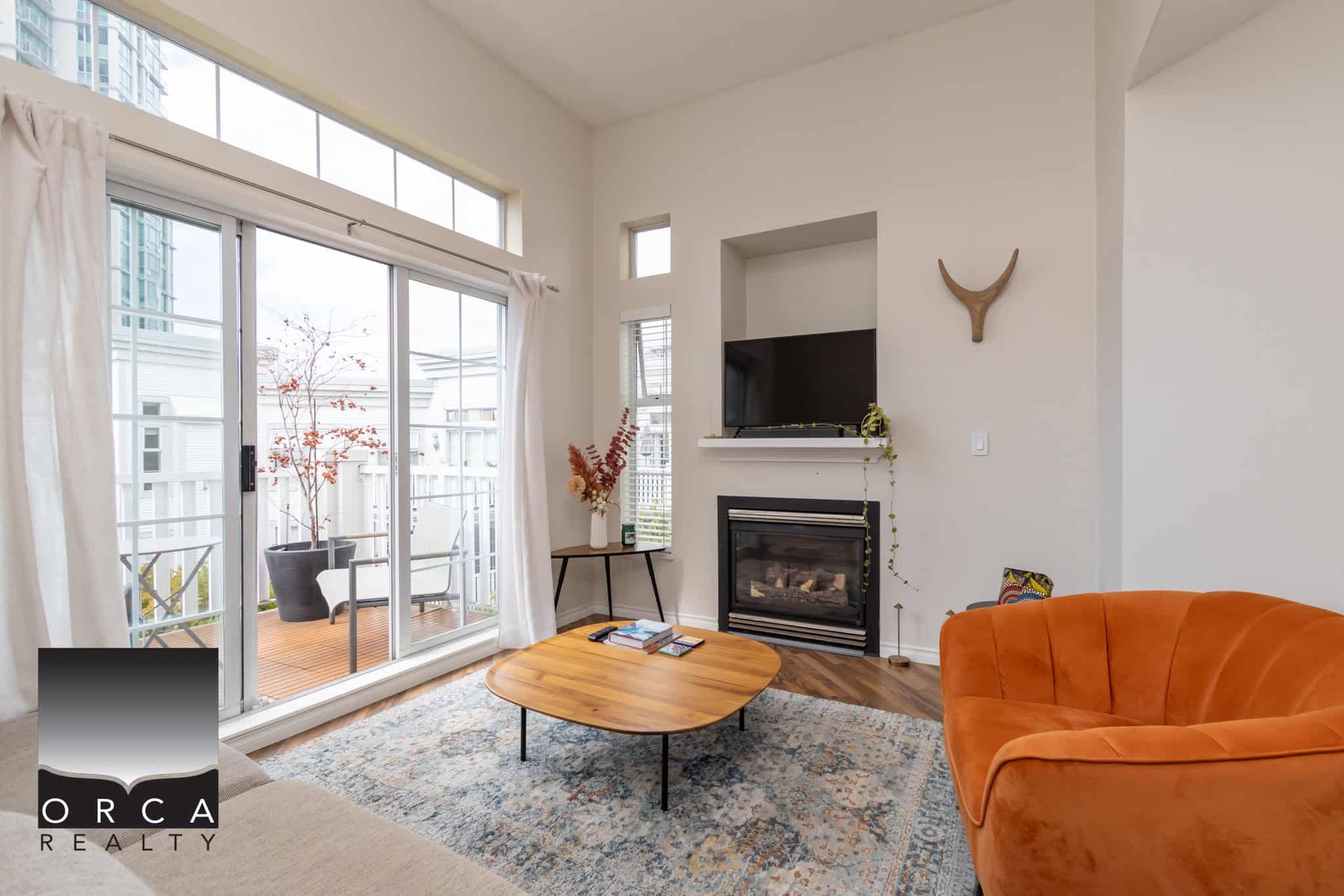 Bright living room with large sliding glass doors leading to a balcony, modern fireplace, and stylish decor, perfect for Vancouver real estate and property buyers seeking contemporary homes.