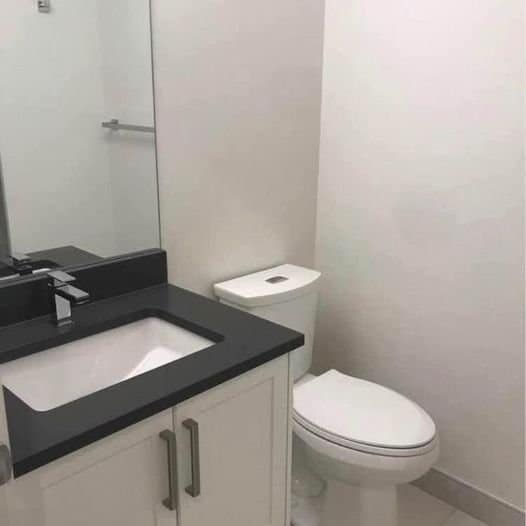 Modern bathroom with white toilet, black countertop, and bathroom vanity – ideal for Vancouver area real estate and property management.