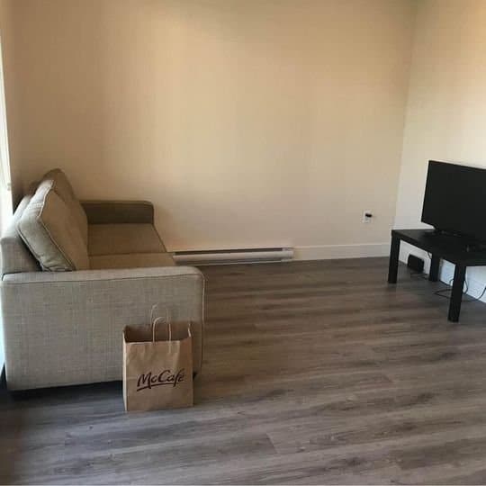Modern living room with beige sofa, flat-screen TV, and minimalist decor, illustrating Orca Realty Inc. property showing in Vancouver. Ideal space for relaxed home viewing.