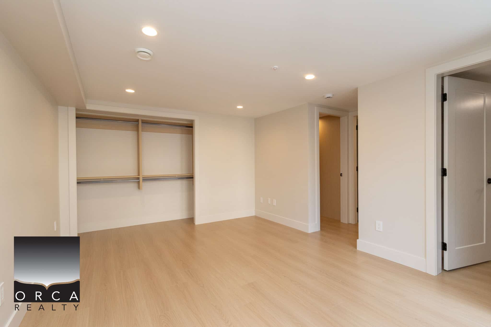 Bright and spacious empty bedroom with light wood flooring, built-in closet, neutral wall colours, and modern lighting, ideal for Vancouver real estate buyers seeking move-in ready homes.