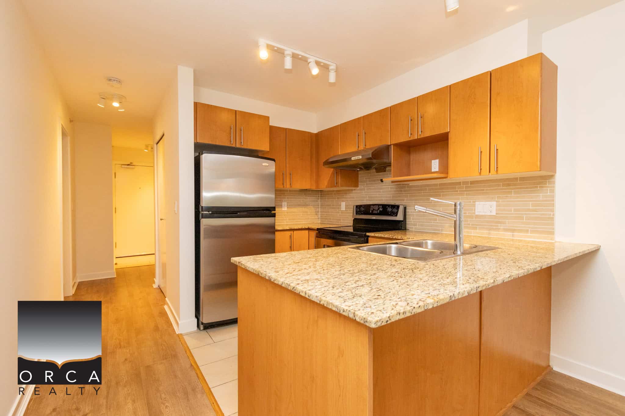 Modern kitchen with granite countertops, stainless steel appliances, and wooden cabinetry in a condo listing by Orca Realty Inc. in BC.