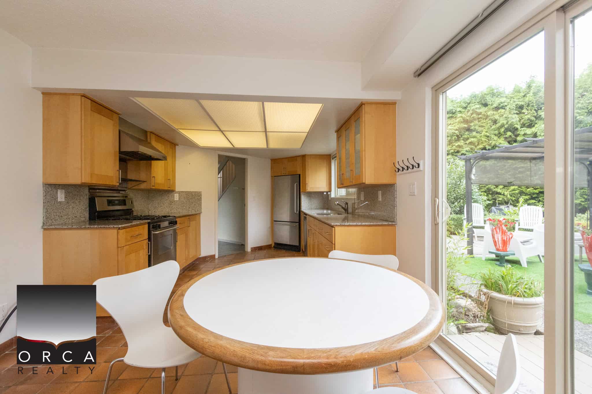 Bright kitchen with wooden cabinets and stainless steel appliances overlooking an outdoor patio in a modern Vancouver home. Perfect for family living and entertaining.
