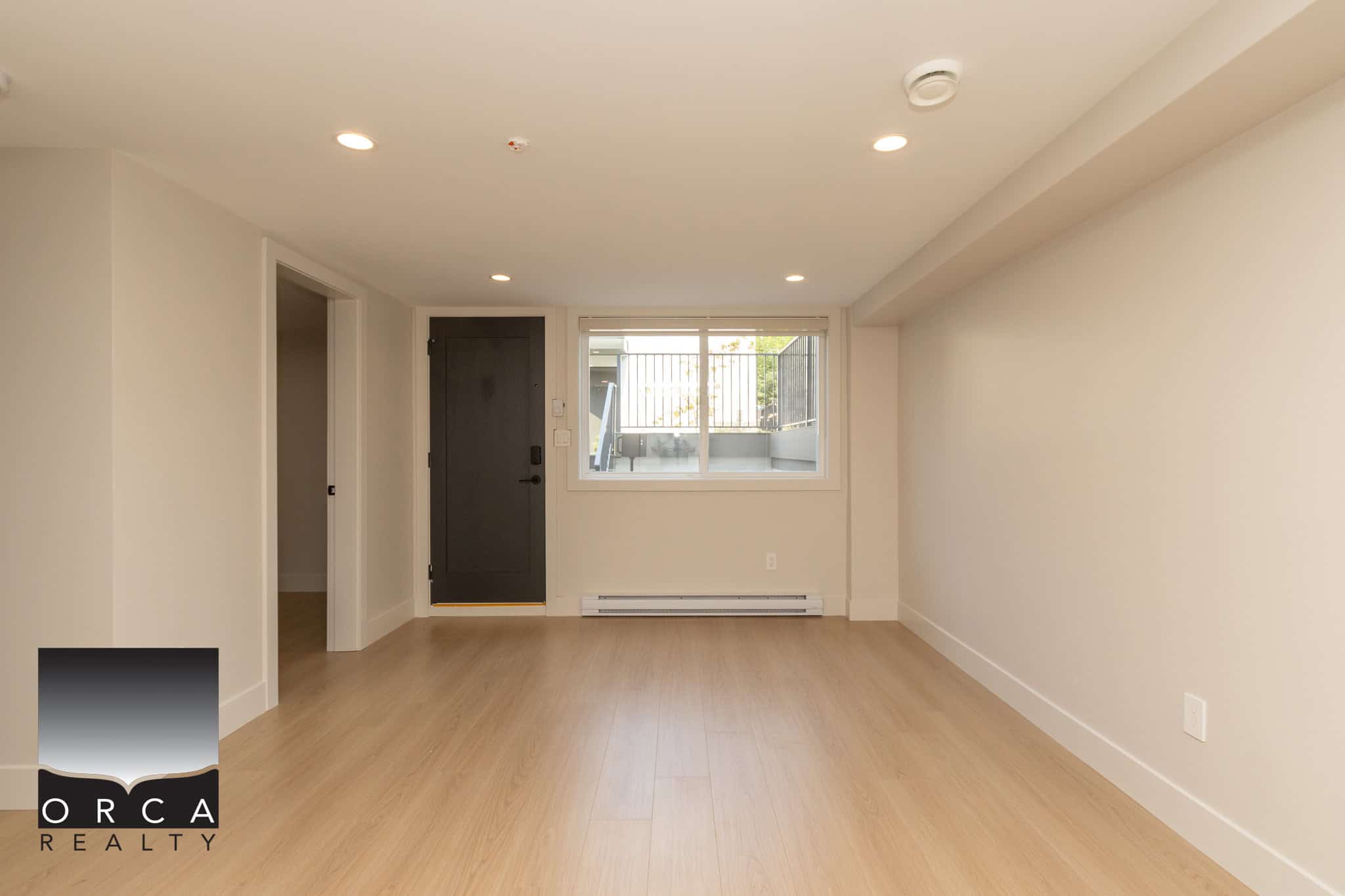 Spacious modern living room with light wood flooring, large window, and neutral wall colours, perfect for Vancouver homebuyers seeking stylish and versatile interior spaces.