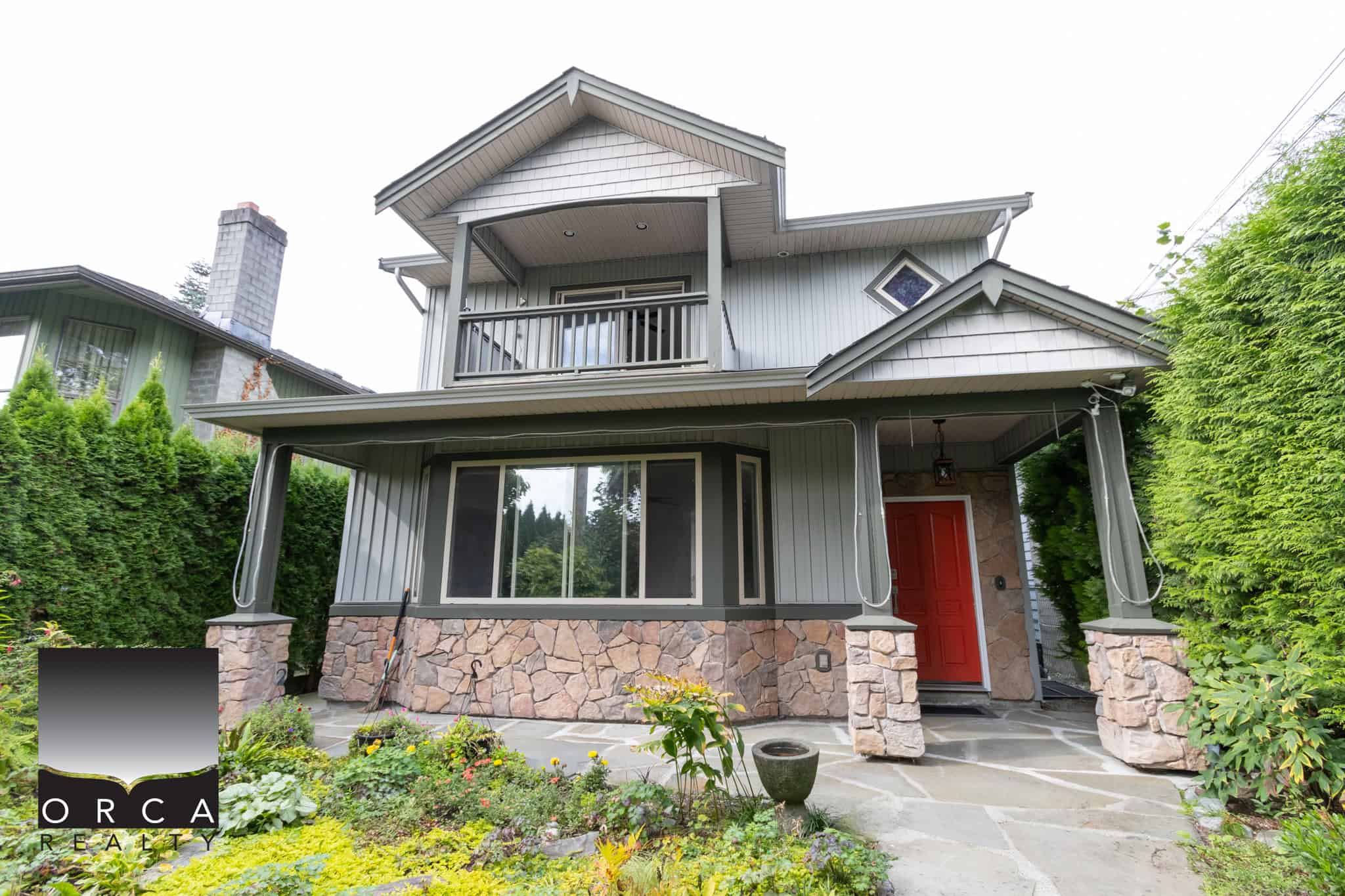 01 Charming two-story home with a colourful garden, stone accents, and a bright red front door, ideal for Vancouver real estate buyers seeking modern family-friendly properties.