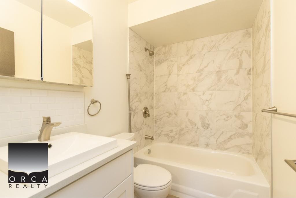 Modern bathroom with marble-tiled shower, sleek vanity, and contemporary fixtures, ideal for Vancouver Island homes. Perfect for buyers seeking stylish, functional properties from Orca Realty Inc.