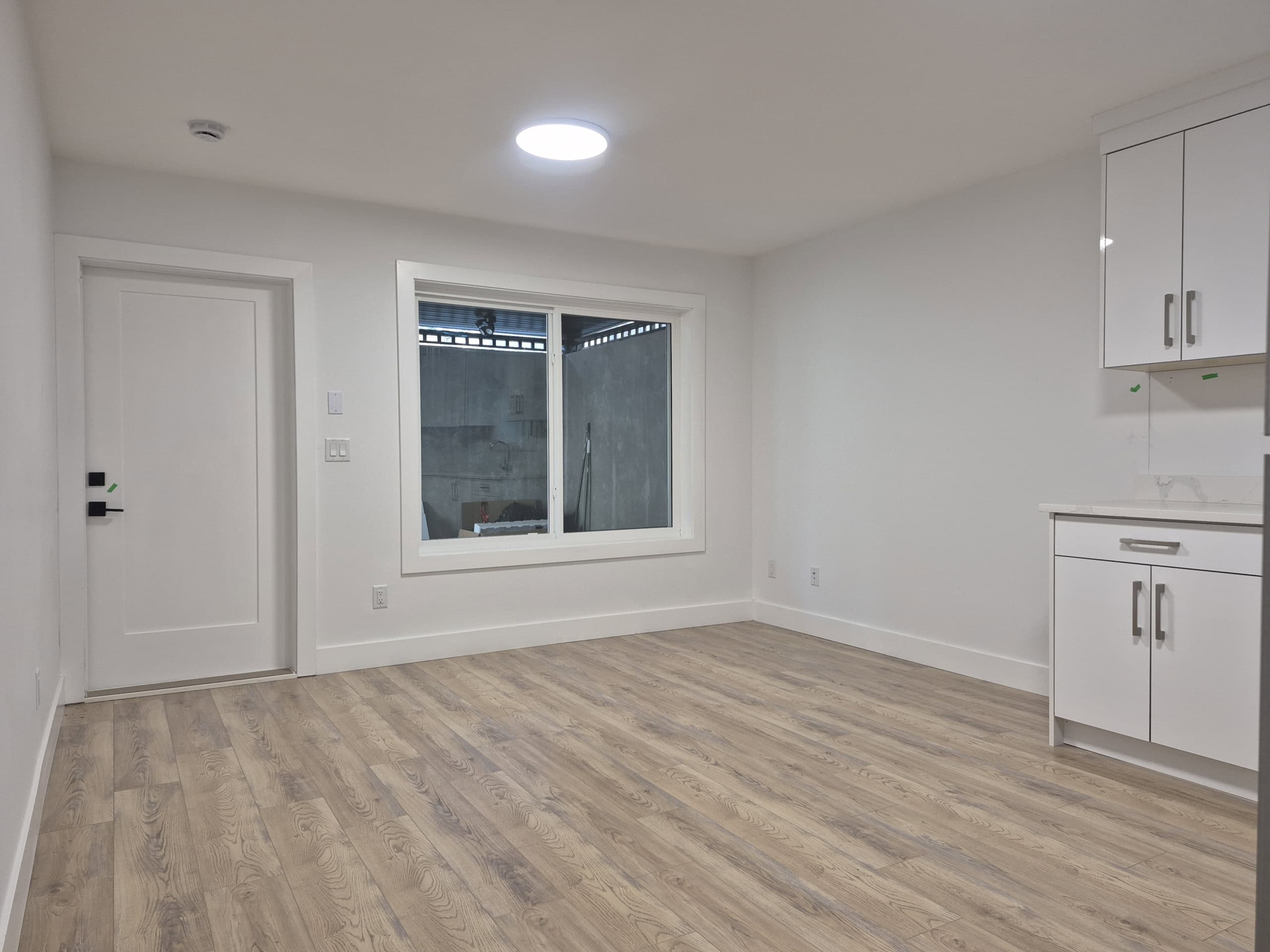 1000055288 Bright modern interior space with white walls, wood flooring, and large window, ideal for real estate showcasing, renovated kitchen, and open-concept living, perfect for homebuyers and investors in Vancouver, BC.