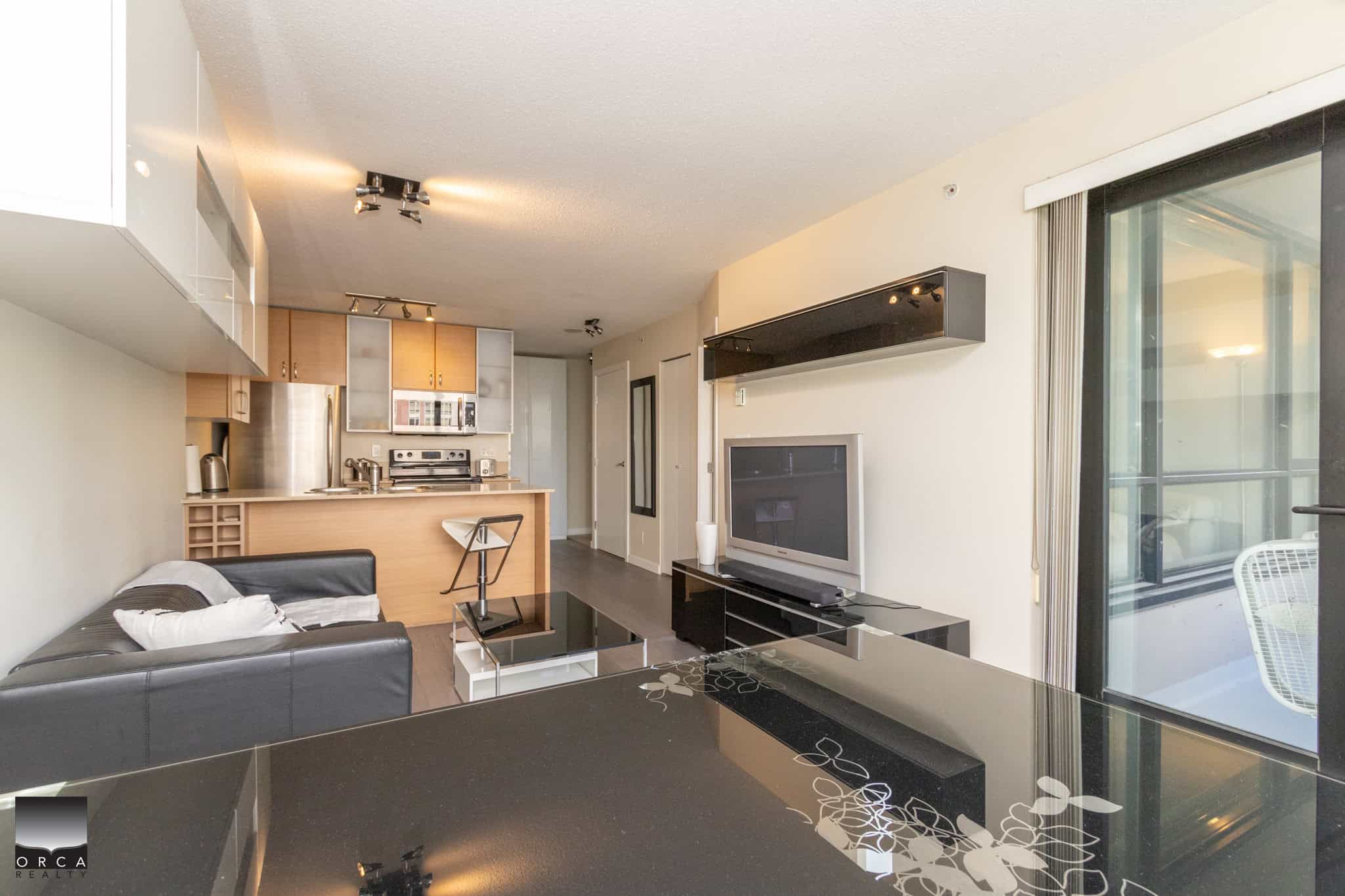 Bright modern Vancouver apartment living room with open-concept kitchen, stylish decor, and balcony access, ideal for real estate investment or relaxing lifestyle.