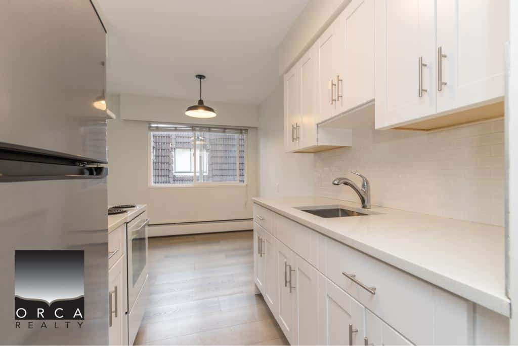 Modern white kitchen with ample cabinetry, stainless steel sink, and natural light, ideal for Vancouver area real estate listings.