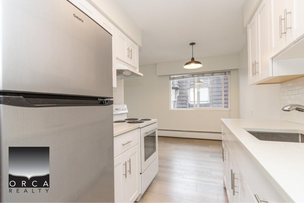 Modern bright kitchen with white cabinets, stainless steel appliances, and ample counter space, perfect for eco-friendly living and real estate investment in Vancouver.